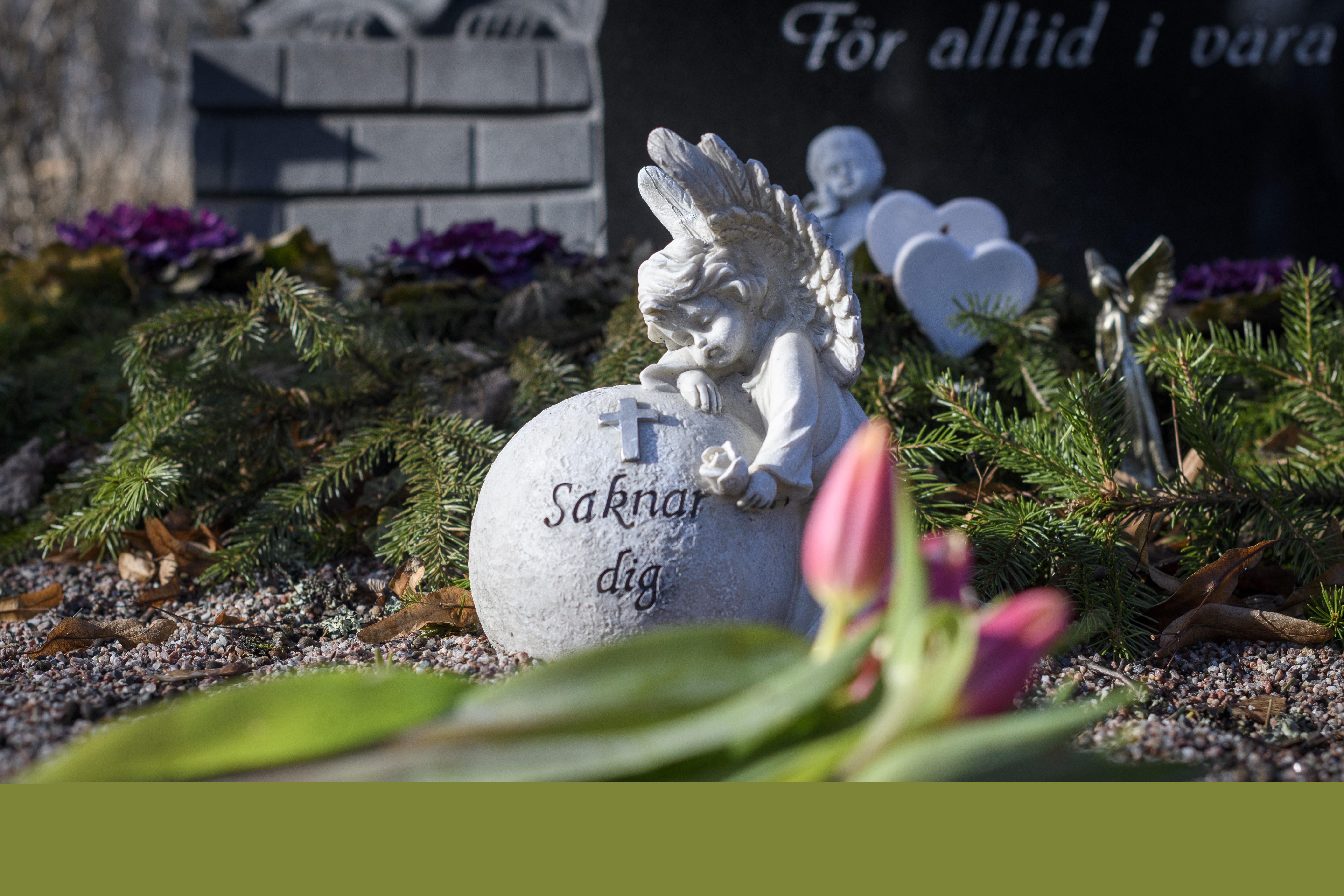 En stenfigur av en ängel och ett klot med texten Saknar dig dekorerar en grav.