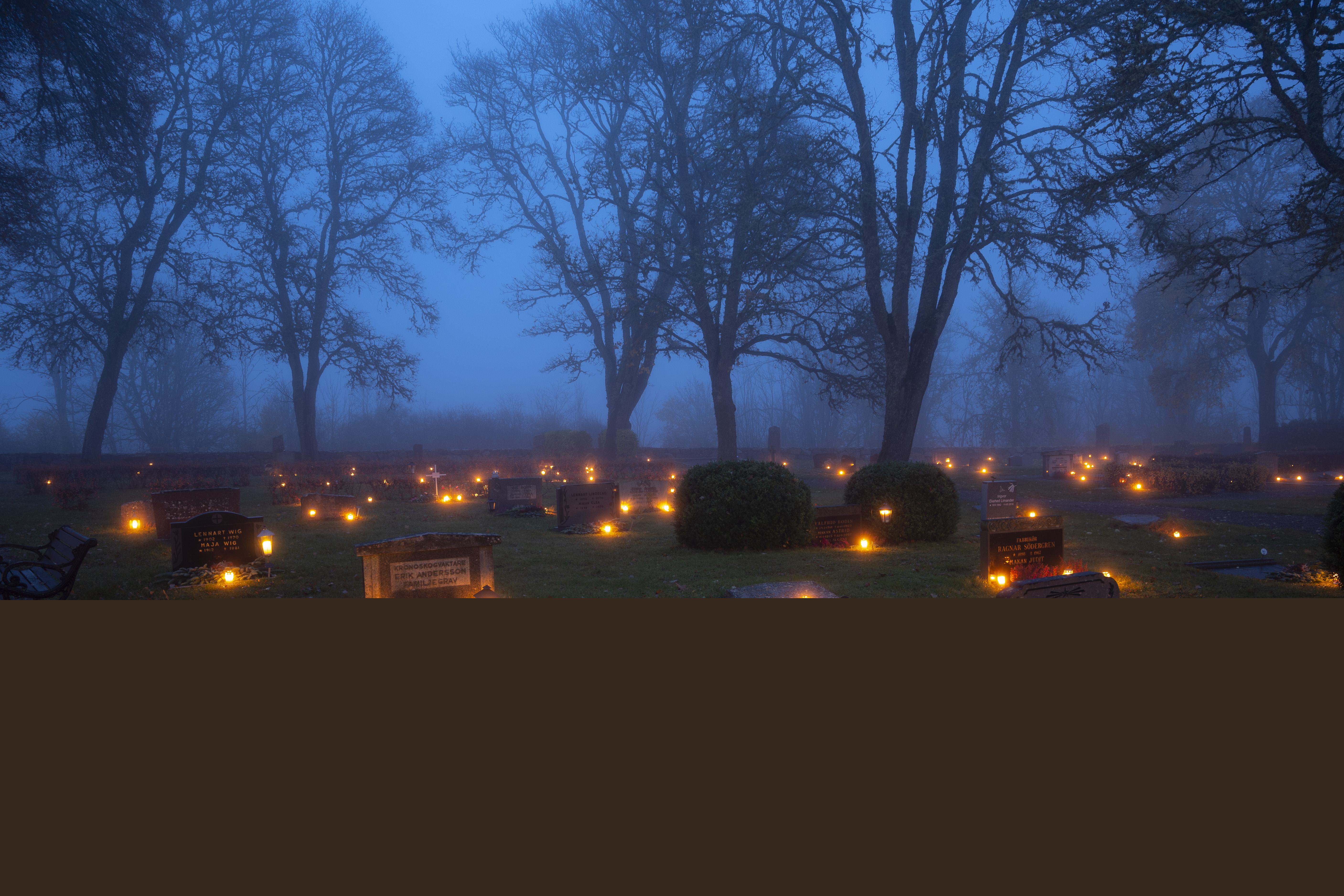 Ljuslyktor lyser på en kyrkogård.