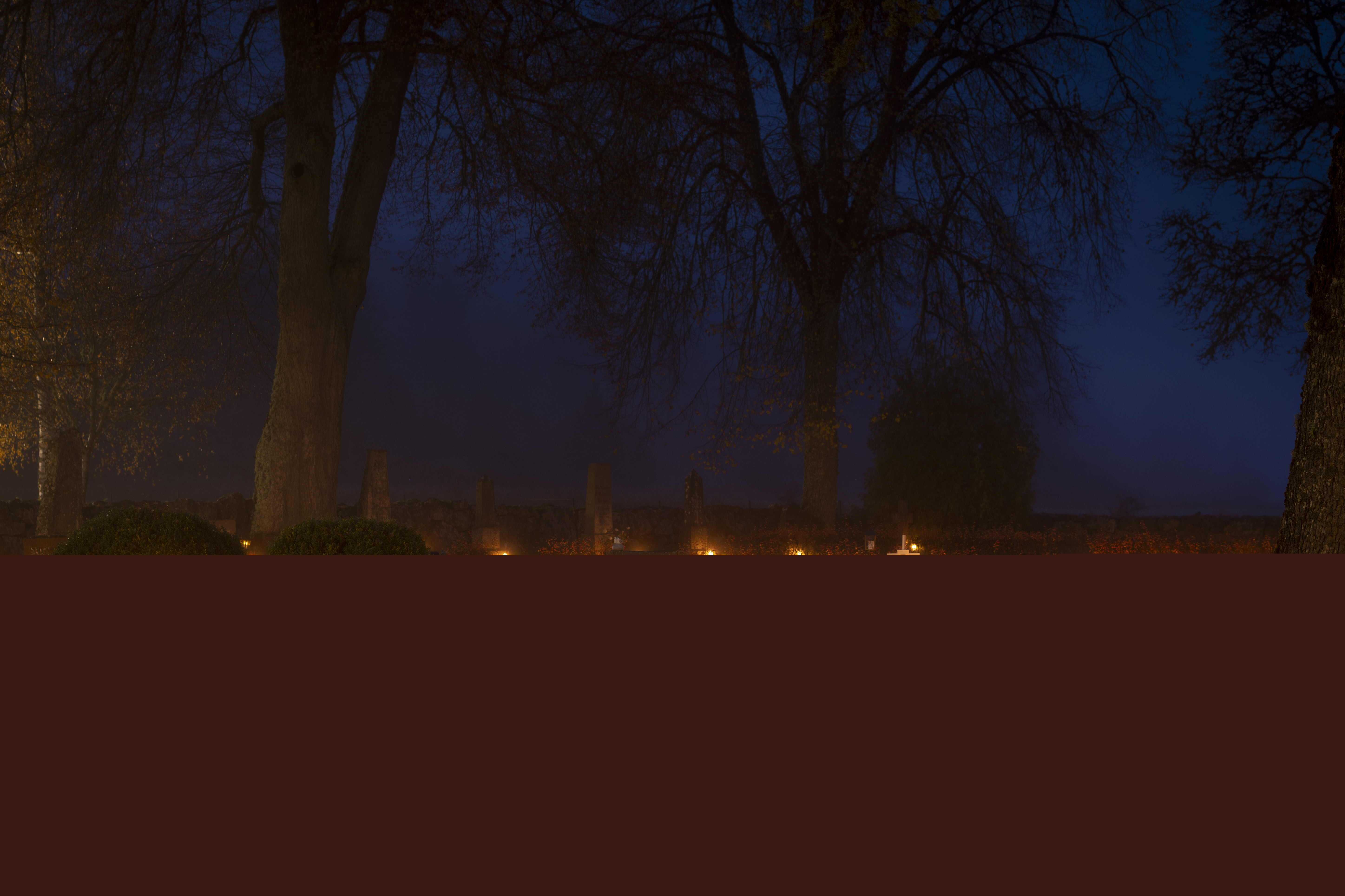 Ljuslyktor lyser på en kyrkogård.