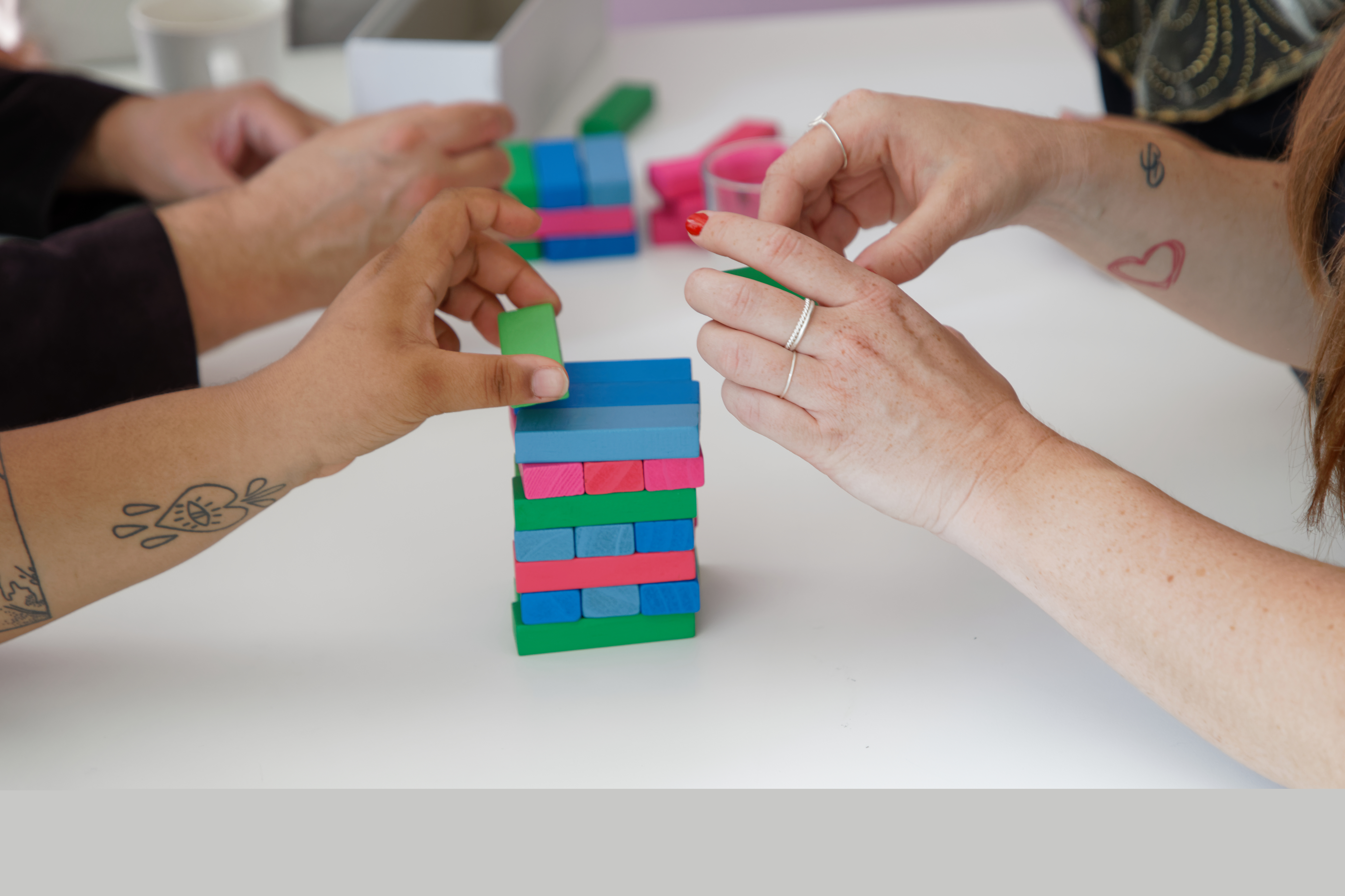 Några personer spelar Jenga med färggranna klossar.