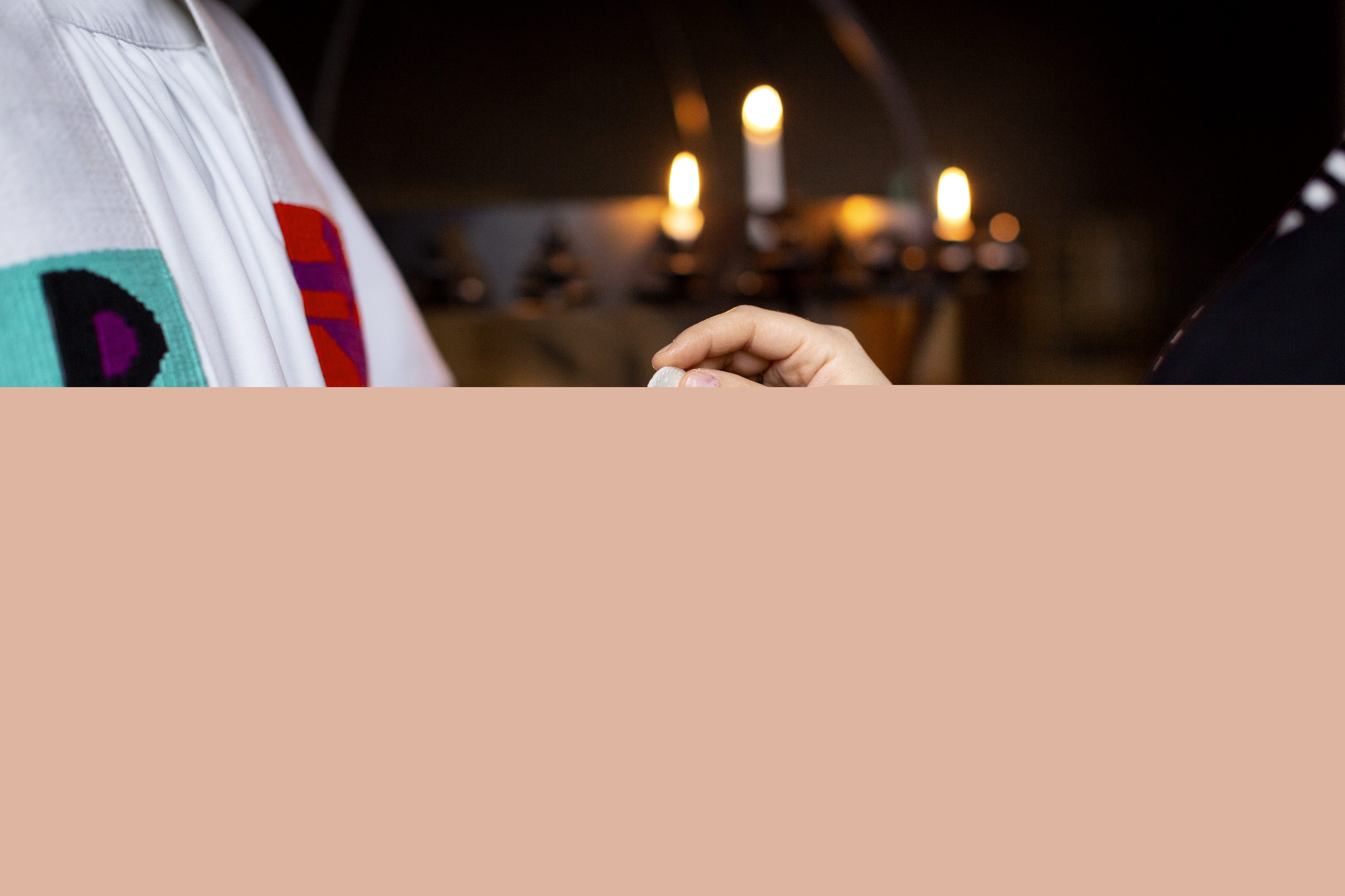 En präst håller fram nattvardskalken och en person doppar sin oblat.