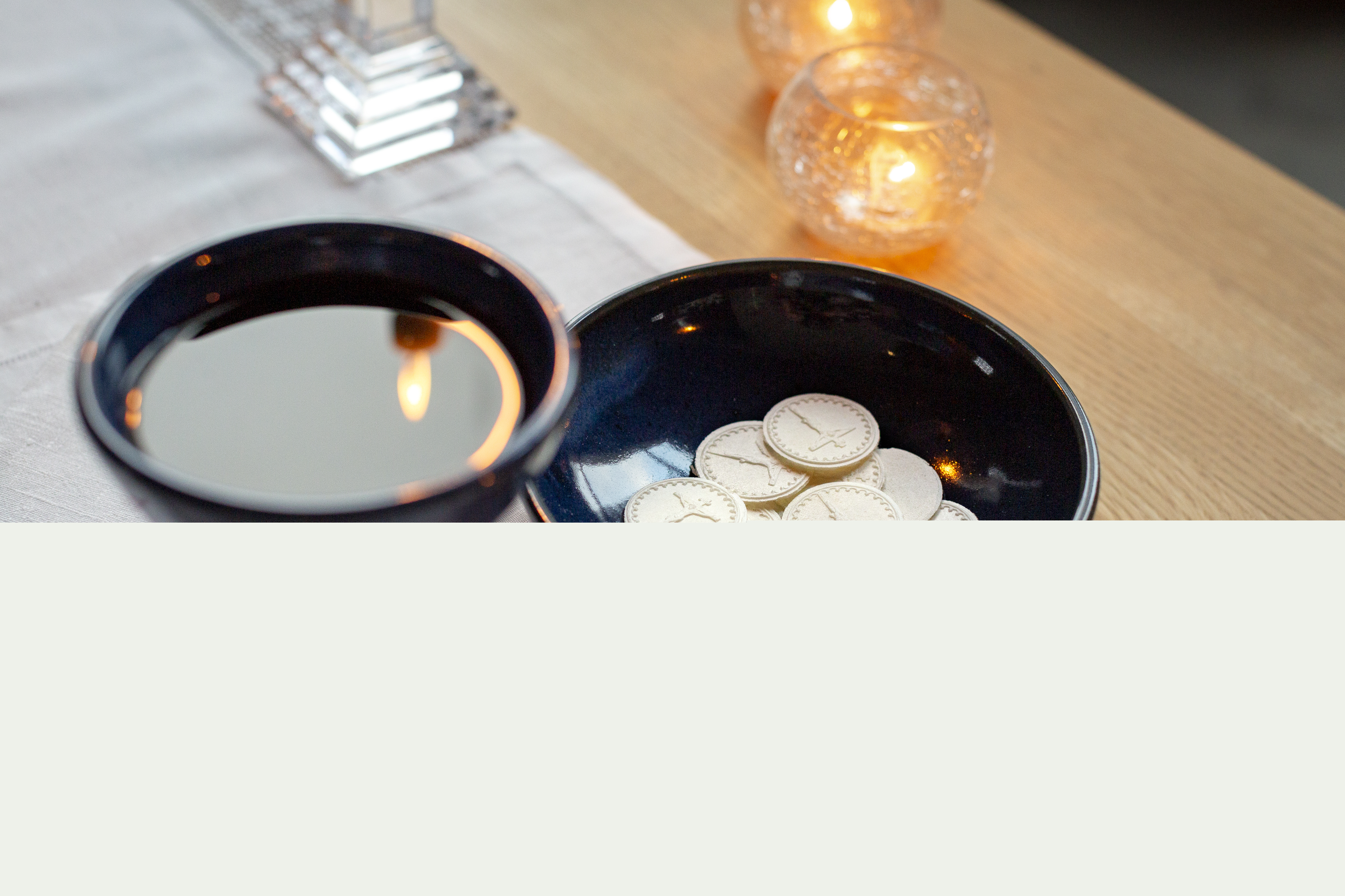 En nattvardskalk med vin och ett fat med oblater står på altaret.