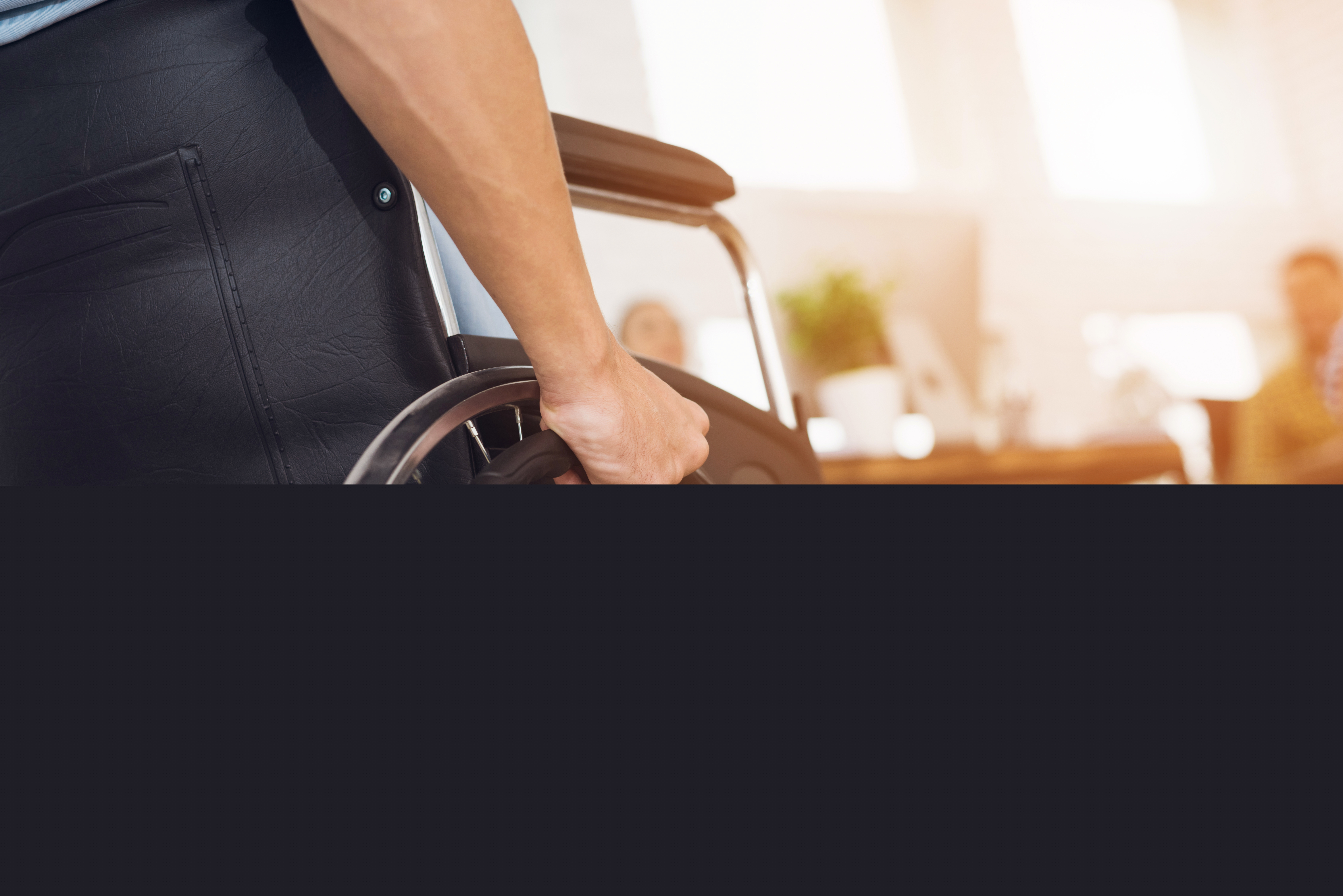 En person i rullstol håller handen runt hjulet.