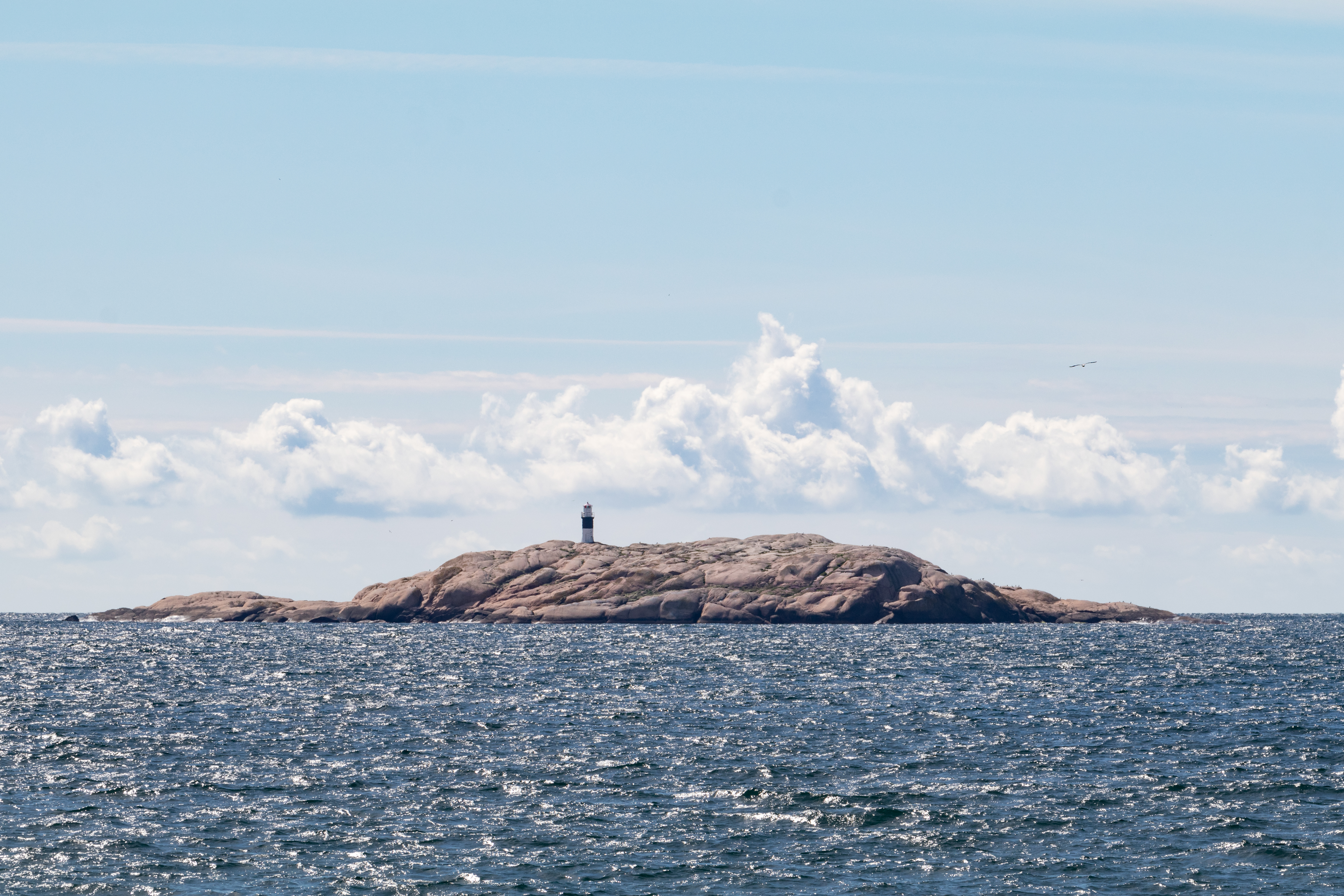 Högst upp på en klippa i havet står en fyr.