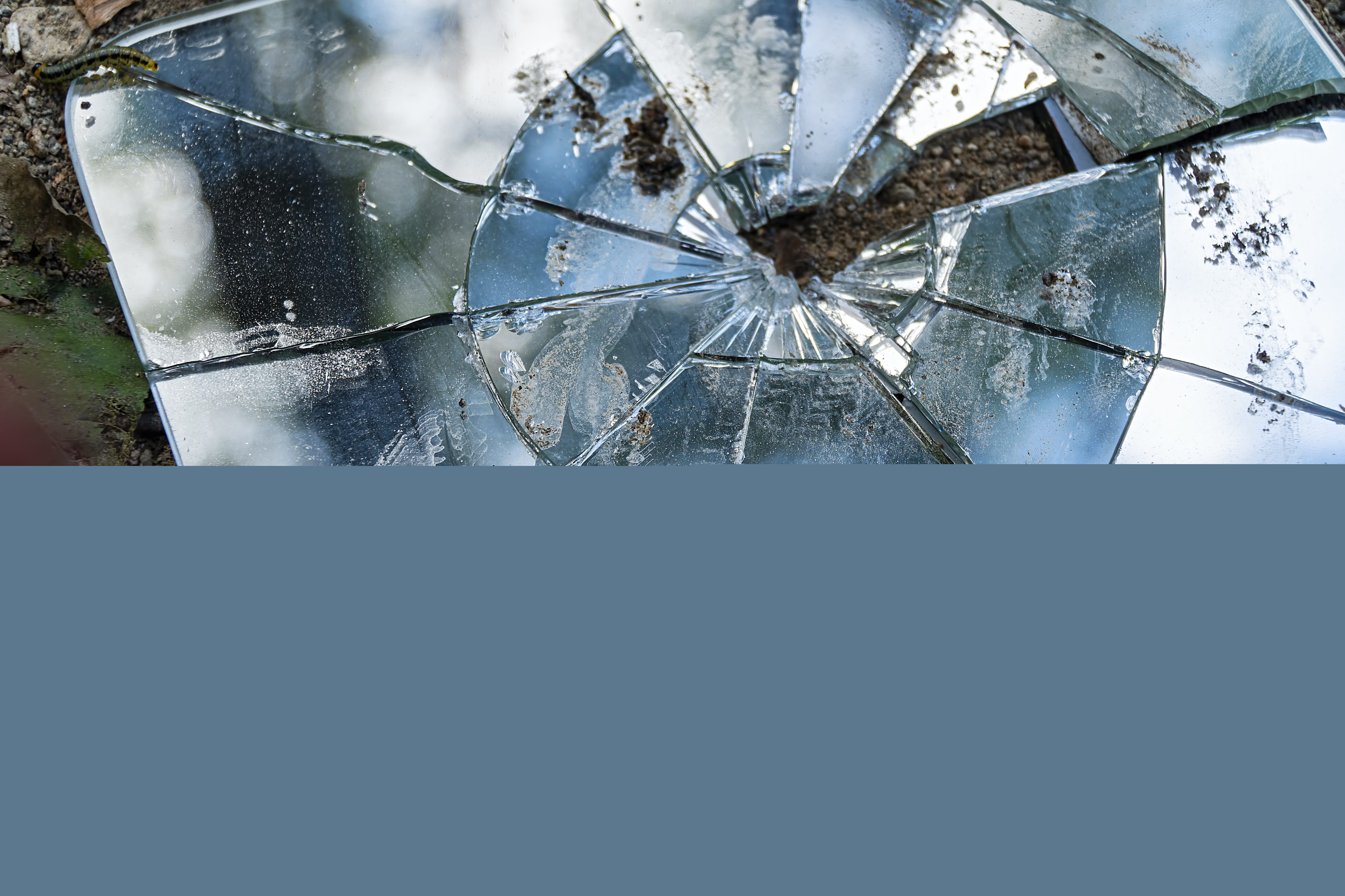 En trasig väggspegel ligger på marken.