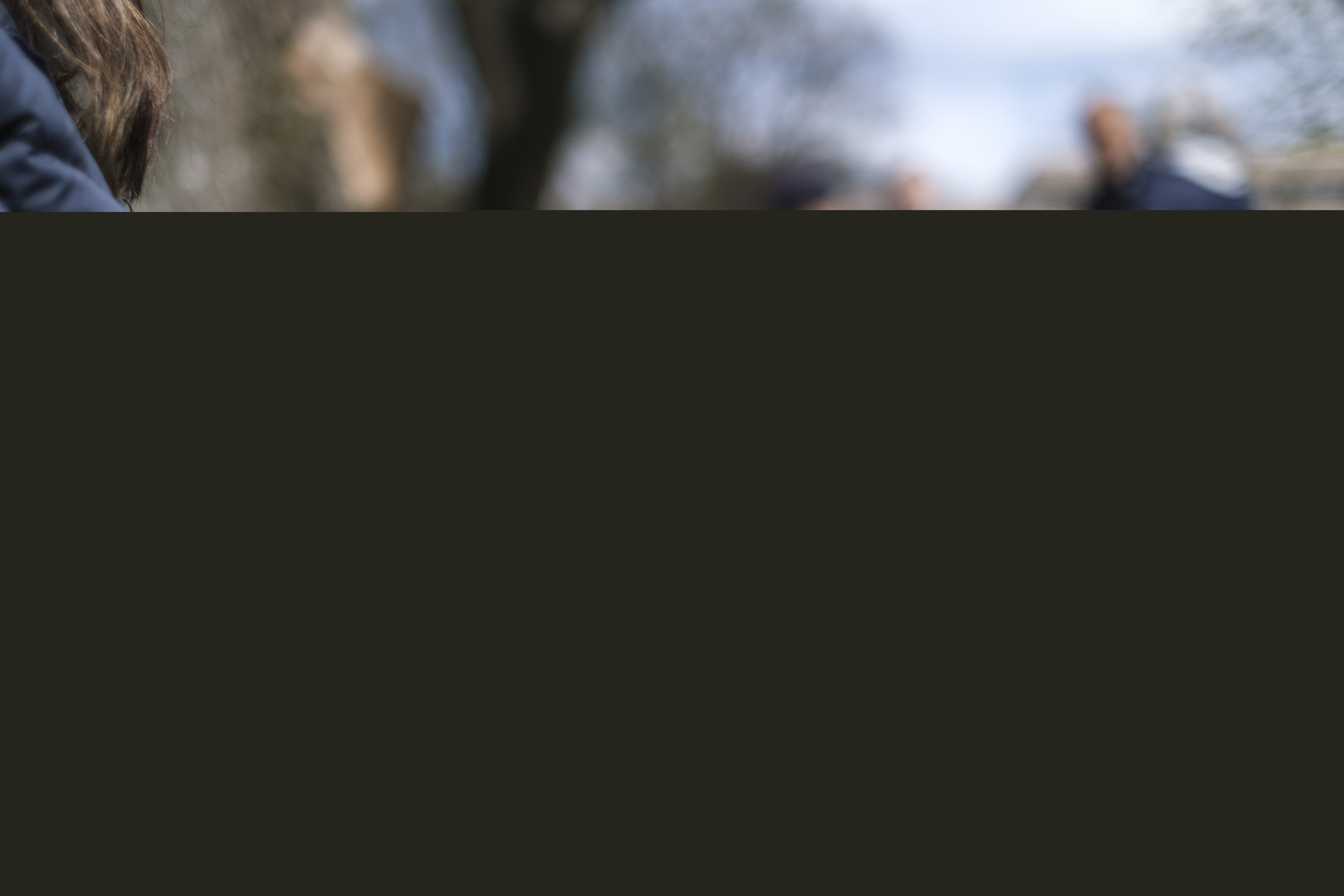 Någon sitter utomhus med en färggrann kopp i händerna.