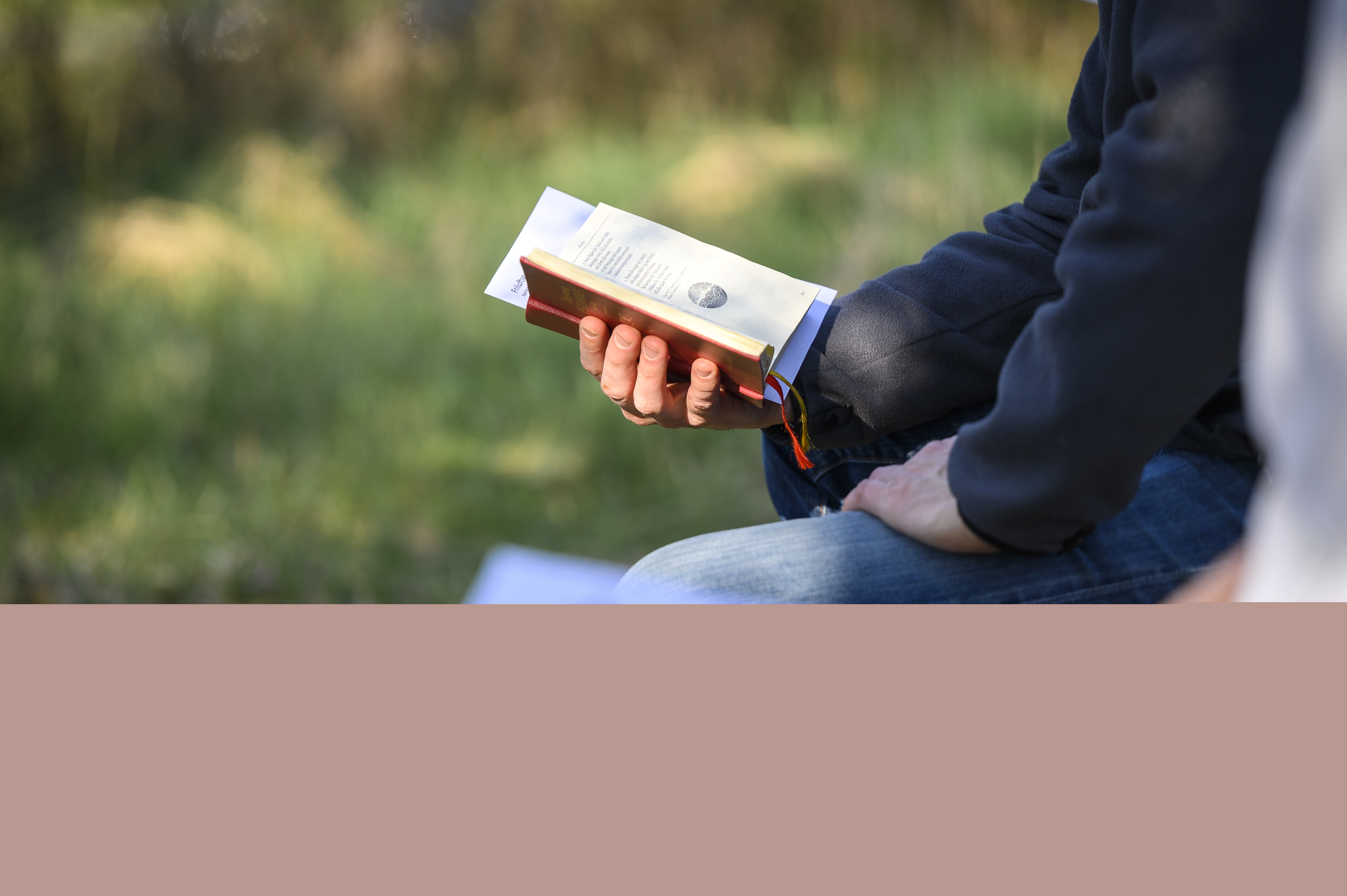 Två personer sitter bredvid varandra utomhus med varsin psalmbok.