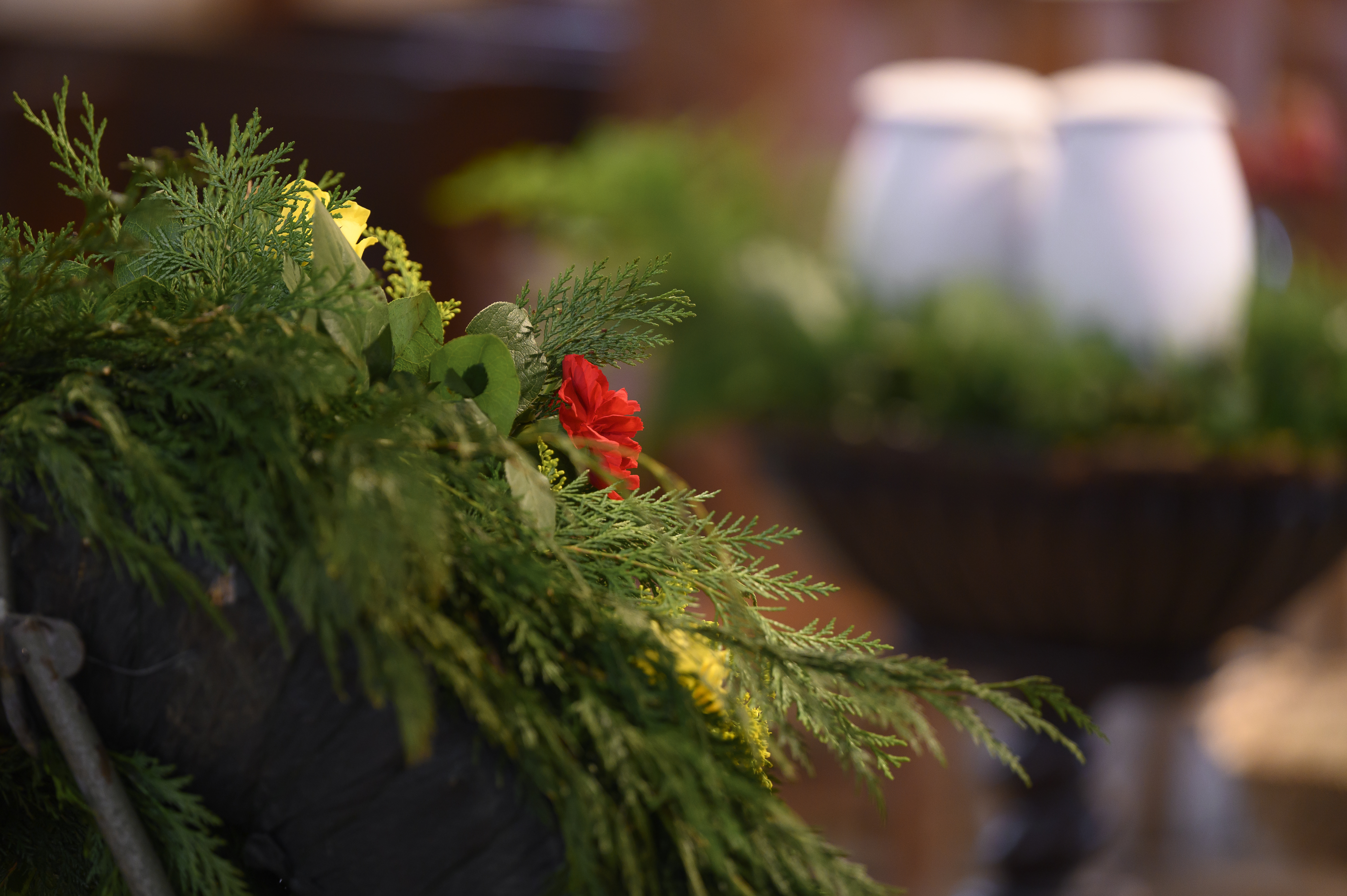 Ett blomsterarrangemang i förgrunden. Längre bort syns två urnor.