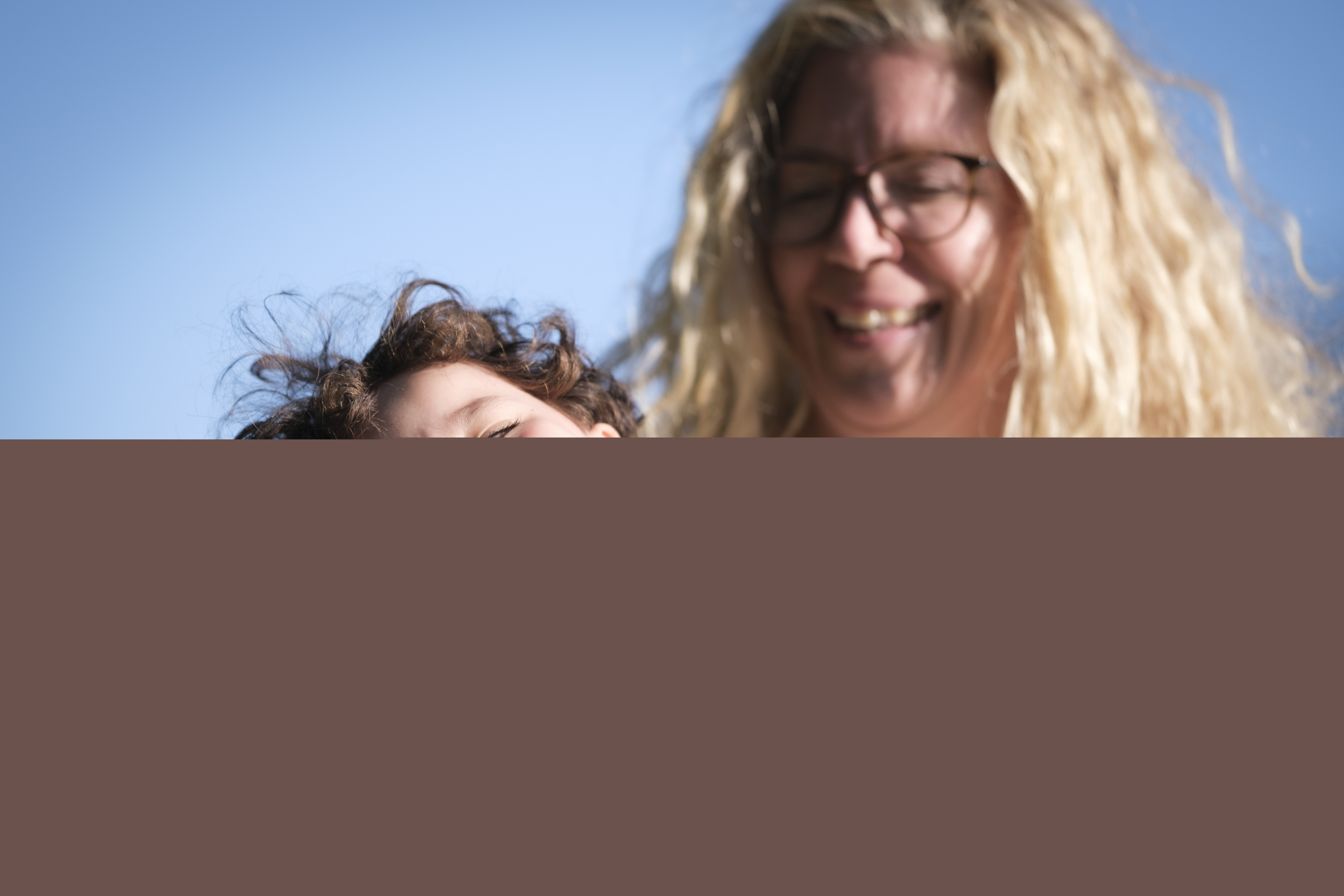 Ett barn gapskrattar i sin mammas knä.