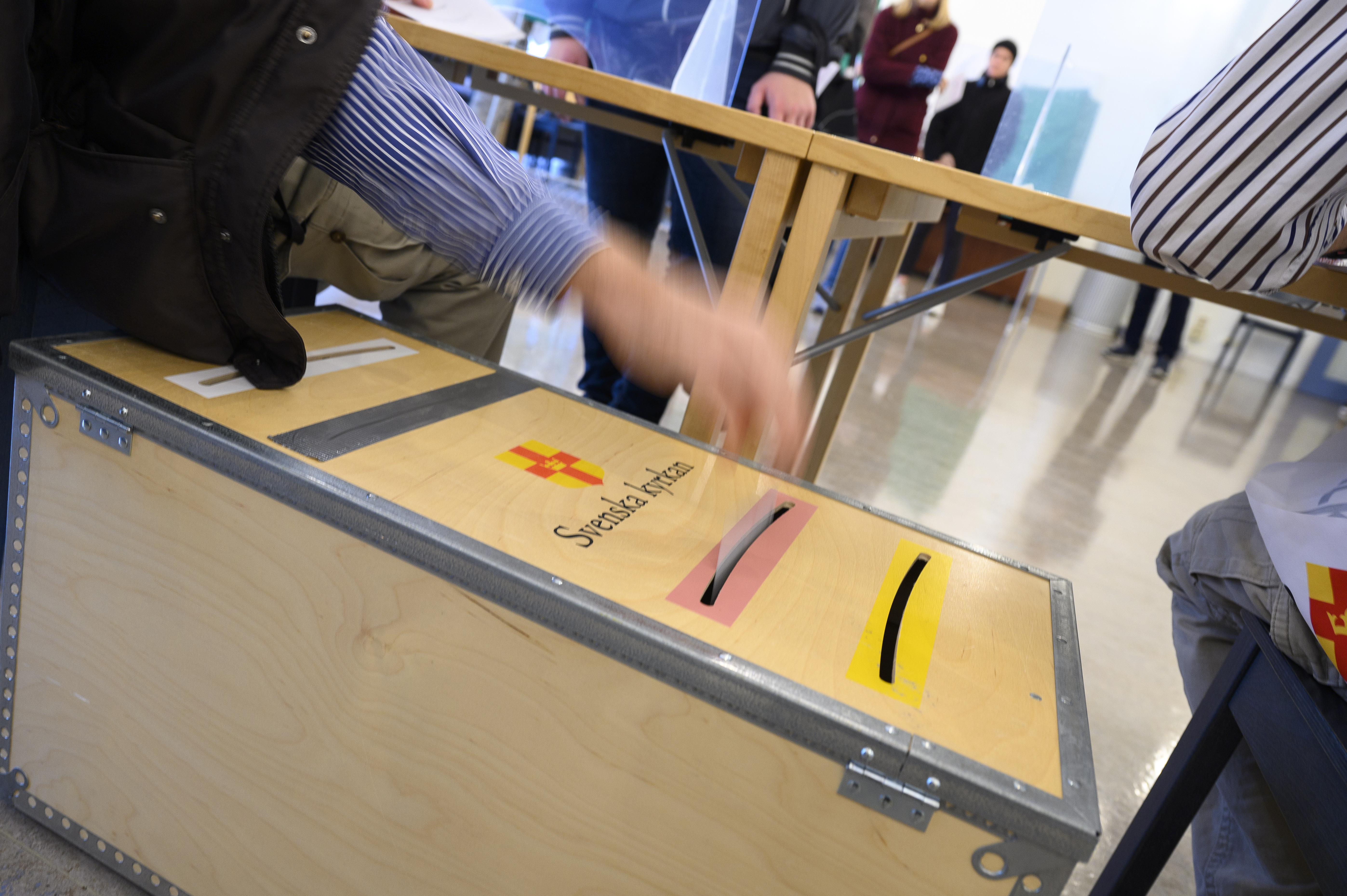 En valarbetare stoppar ner ett valkuvert i en valurna.
