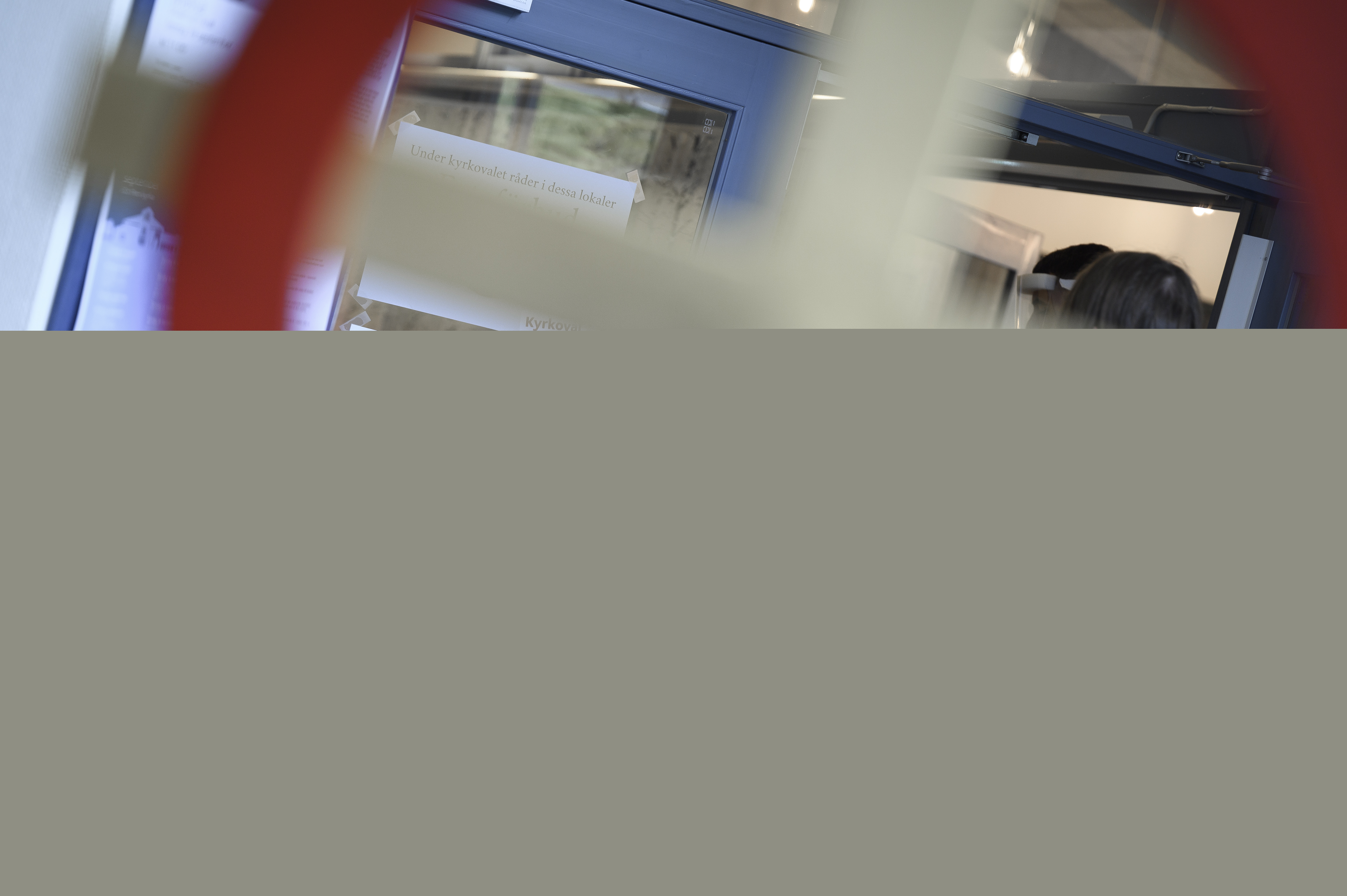 En skylt med texten Vallokal sitter på en dörr. Ett kors i förgrunden.