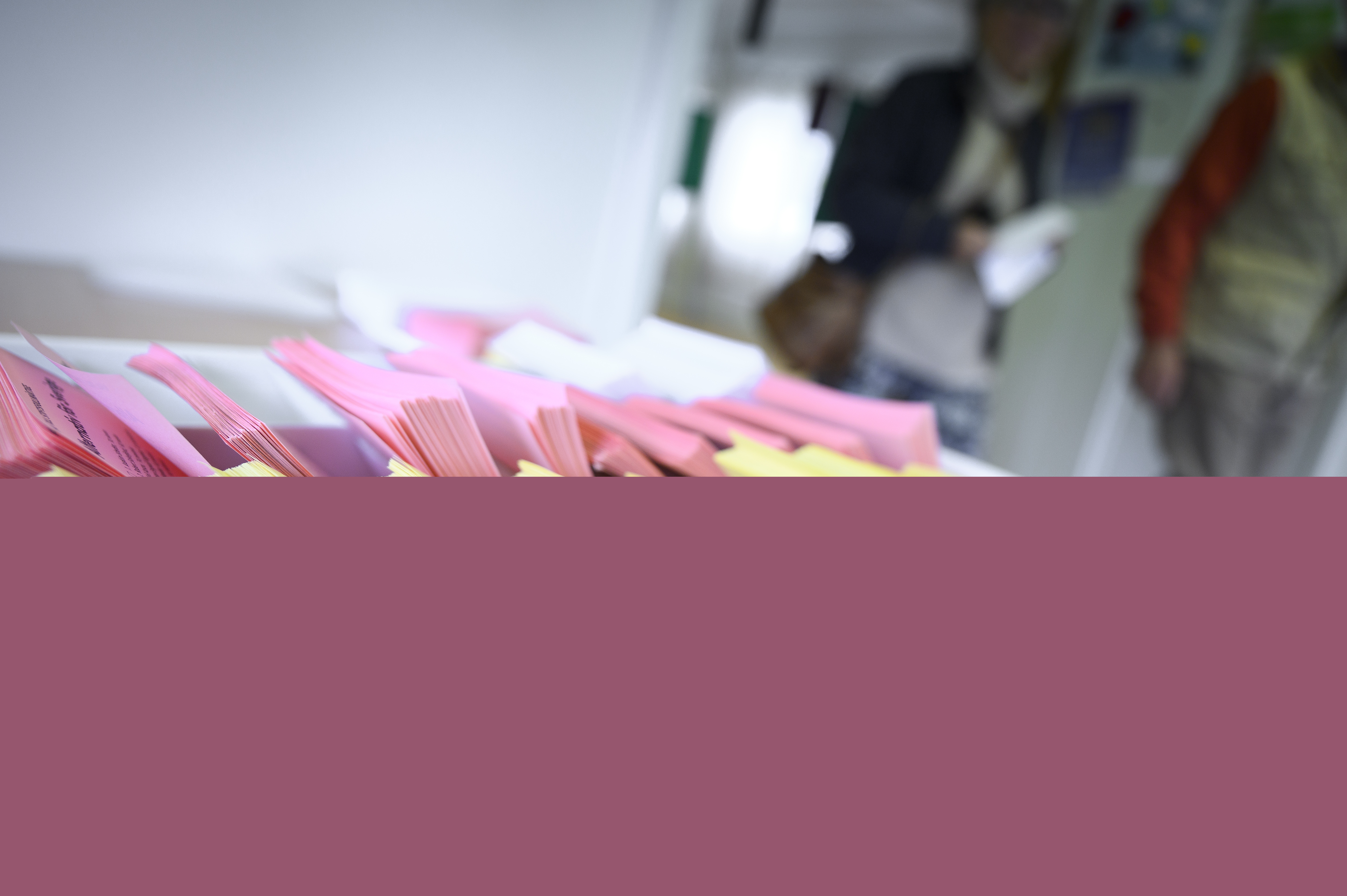 Närbild på en låda med färgsorterade röstsedlar.