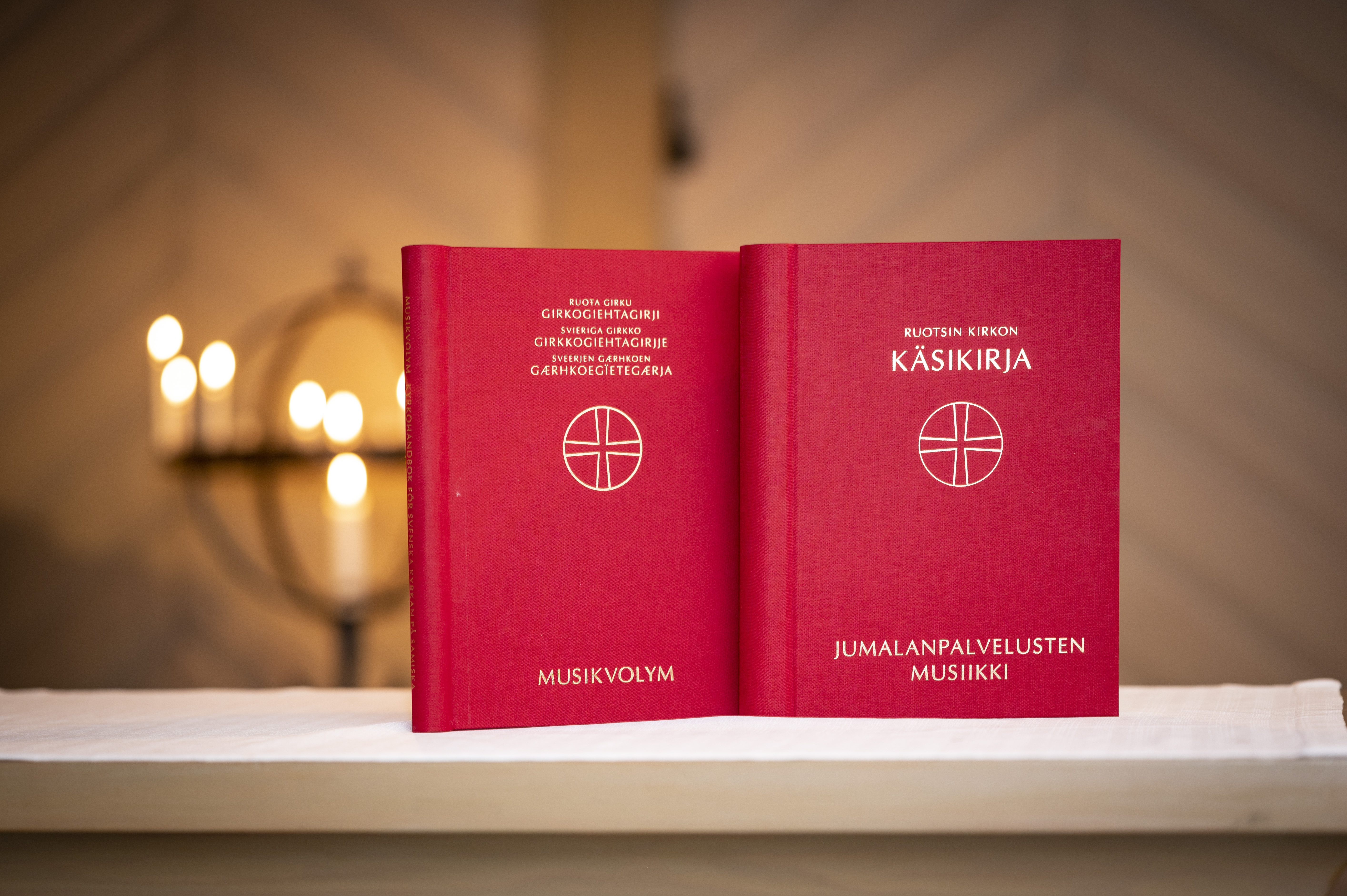 Två kyrkliga publikationer på minoritetsspråk står uppställda på ett bord i en kyrka.