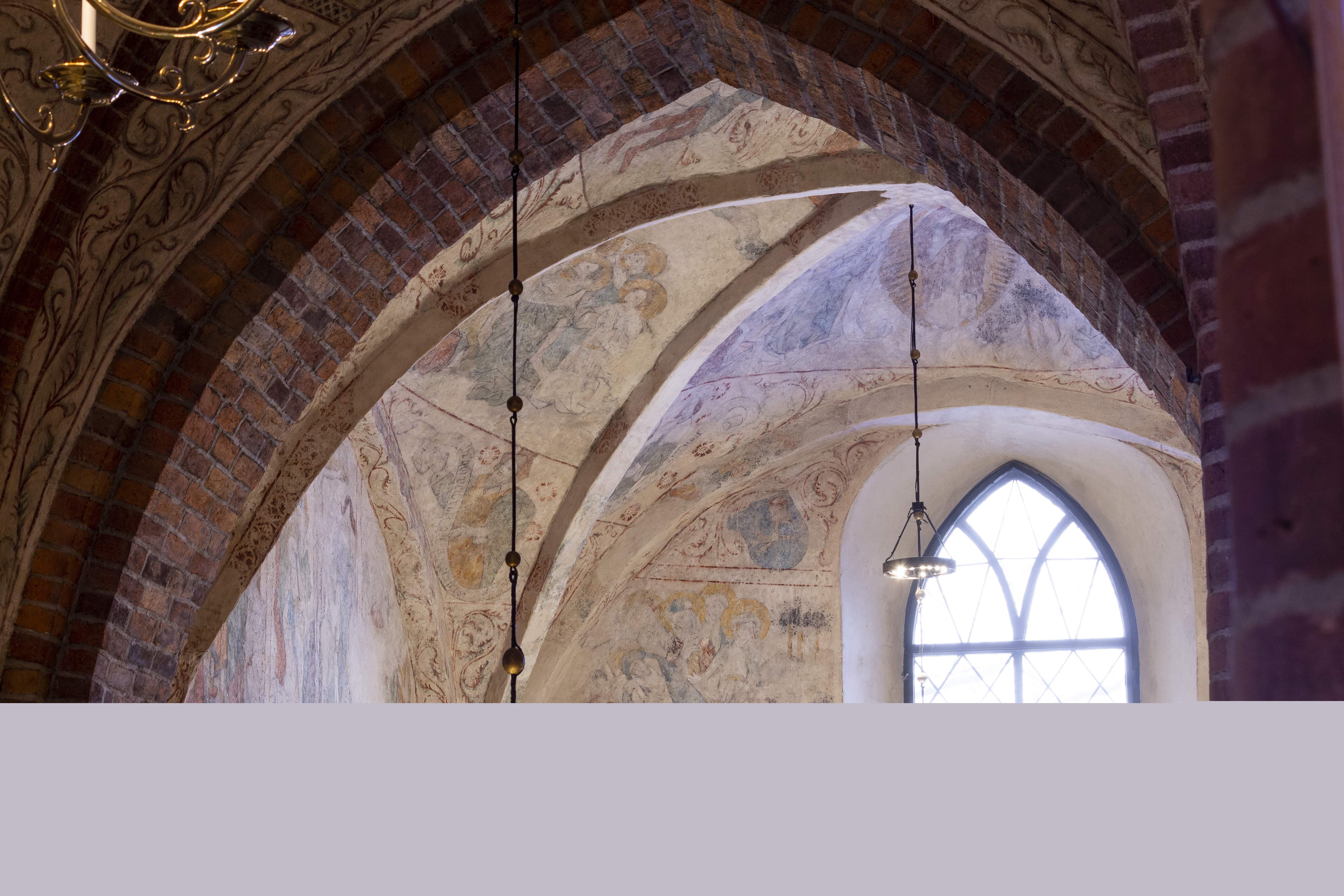 Gamla takmålningar i en tegelkyrka.