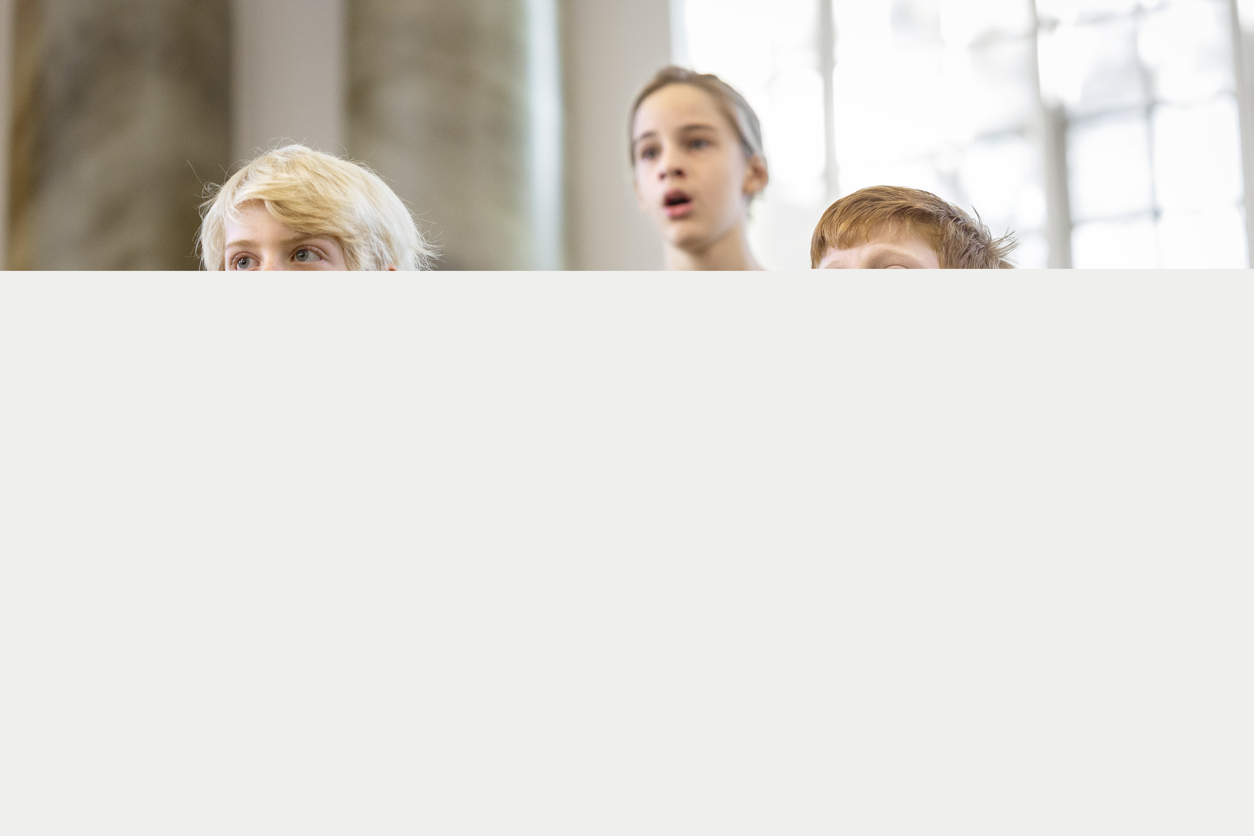 Närbild på medlemmar i en barnkör som sjunger i en kyrka.