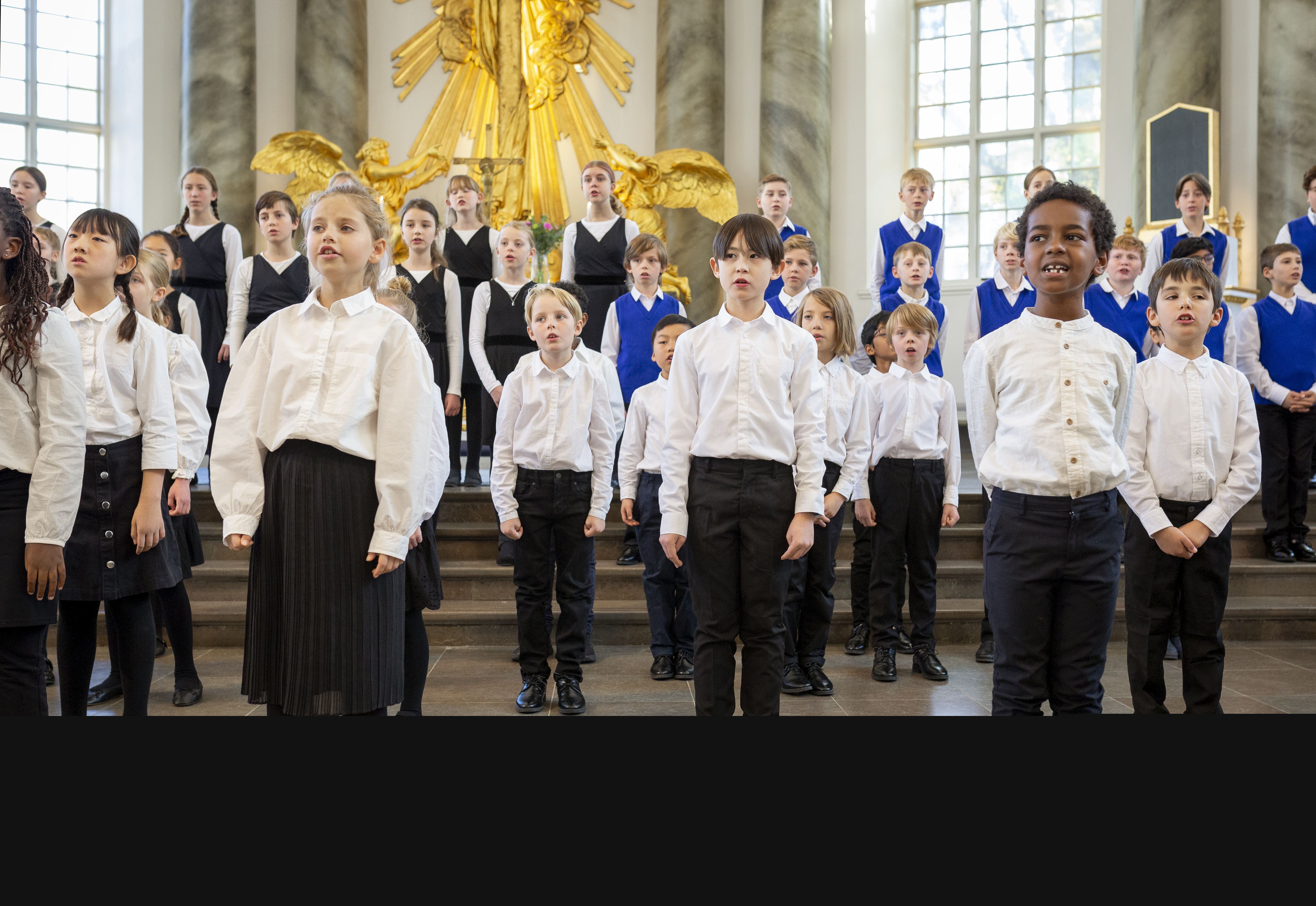 En barnkör står och sjunger framme i kyrkans kor.