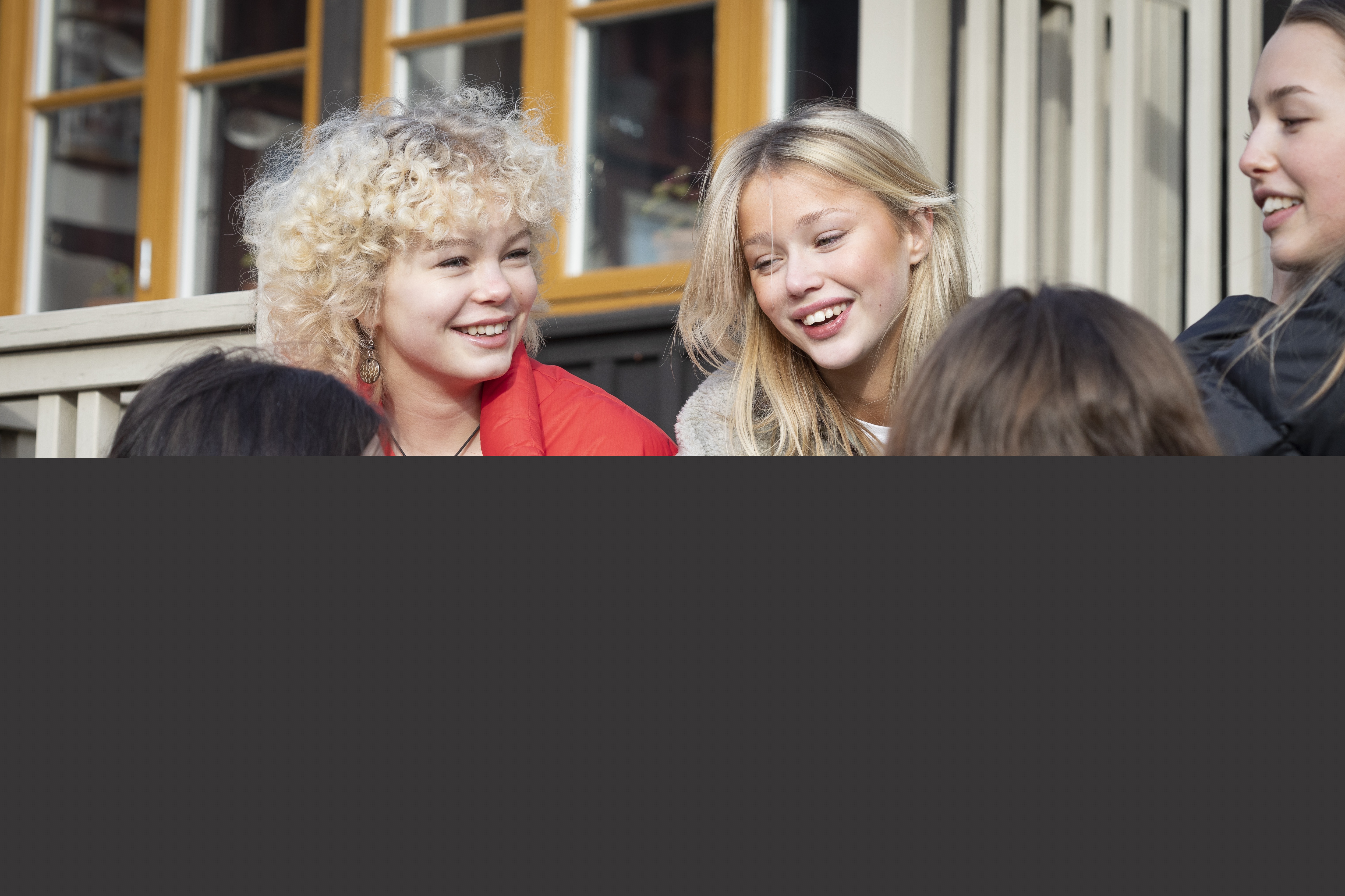 Några tonårstjejer sitter på en hustrappa.