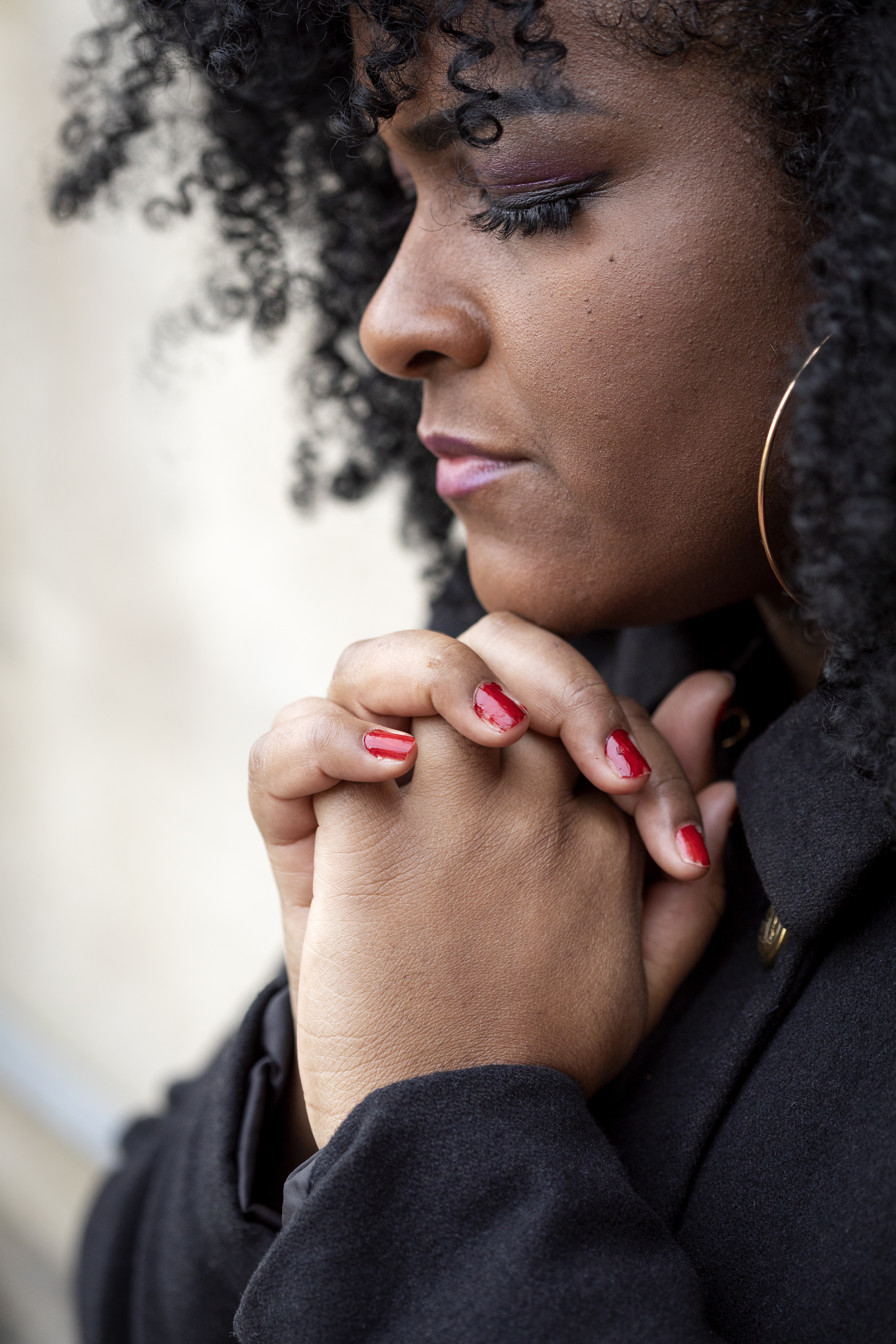 Närbild på en kvinna med slutna ögon och knäppta händer.