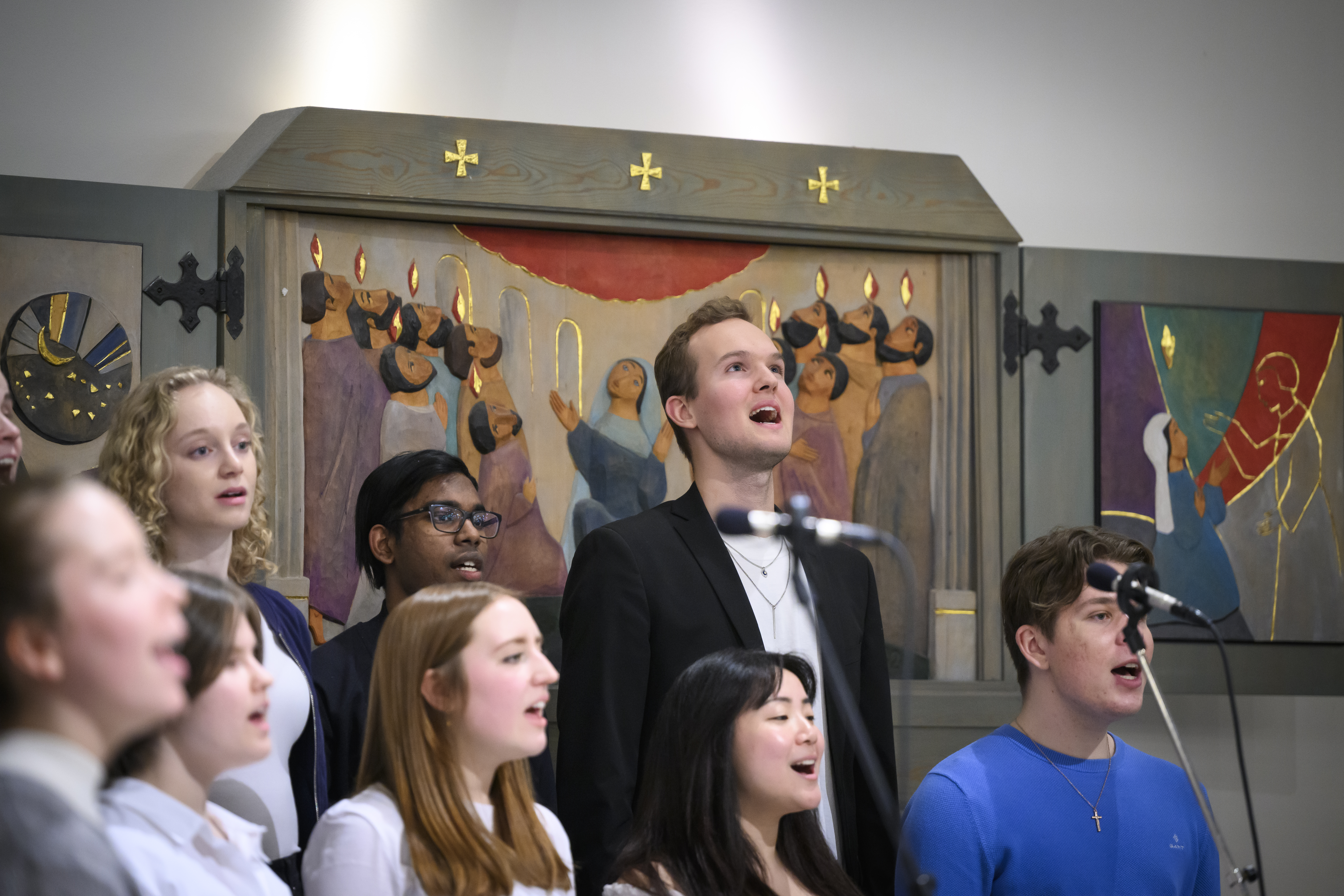 En blandad ungdomskör sjunger i en kyrka.