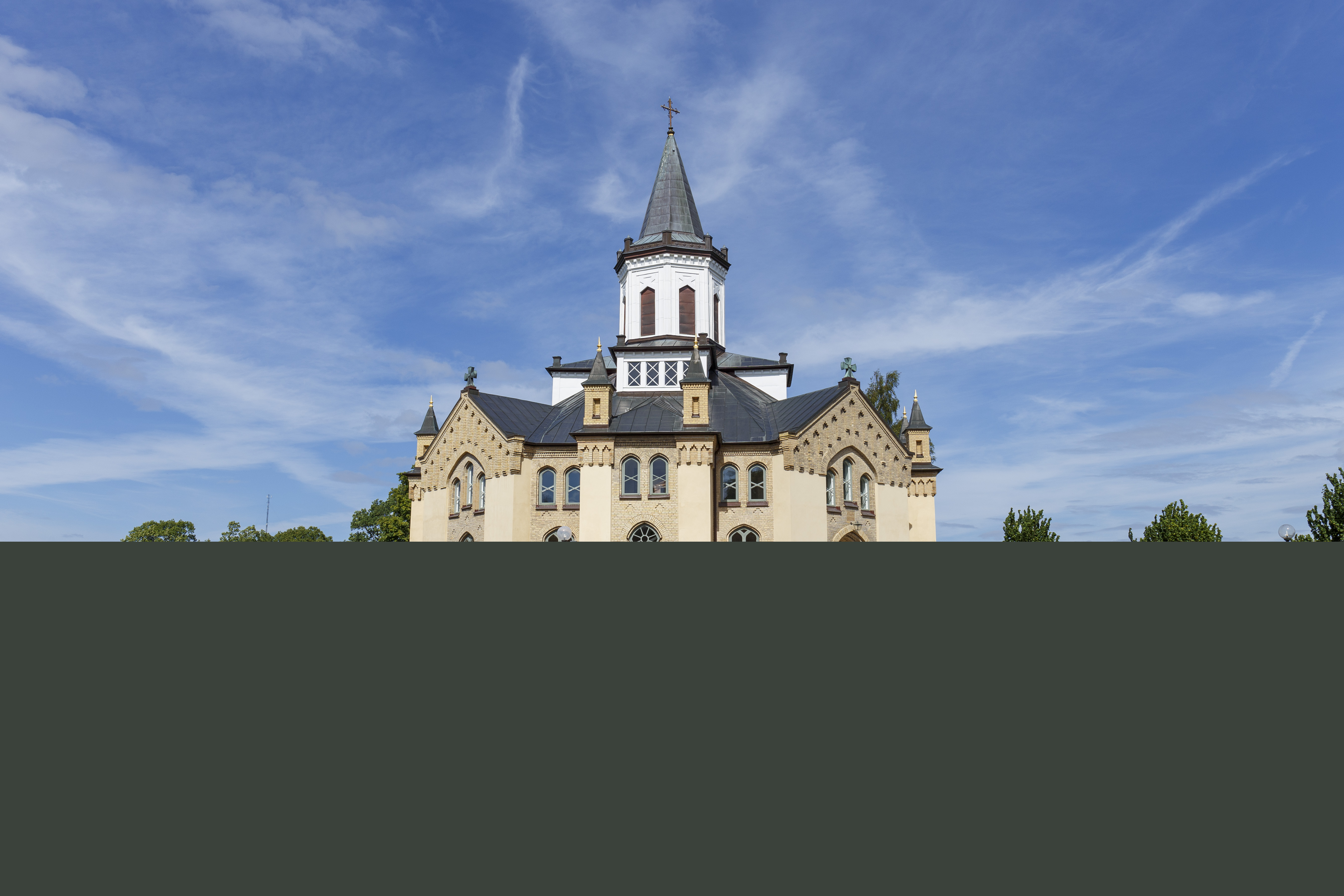 En åttkantig kyrka och en kyrkogård i solen.