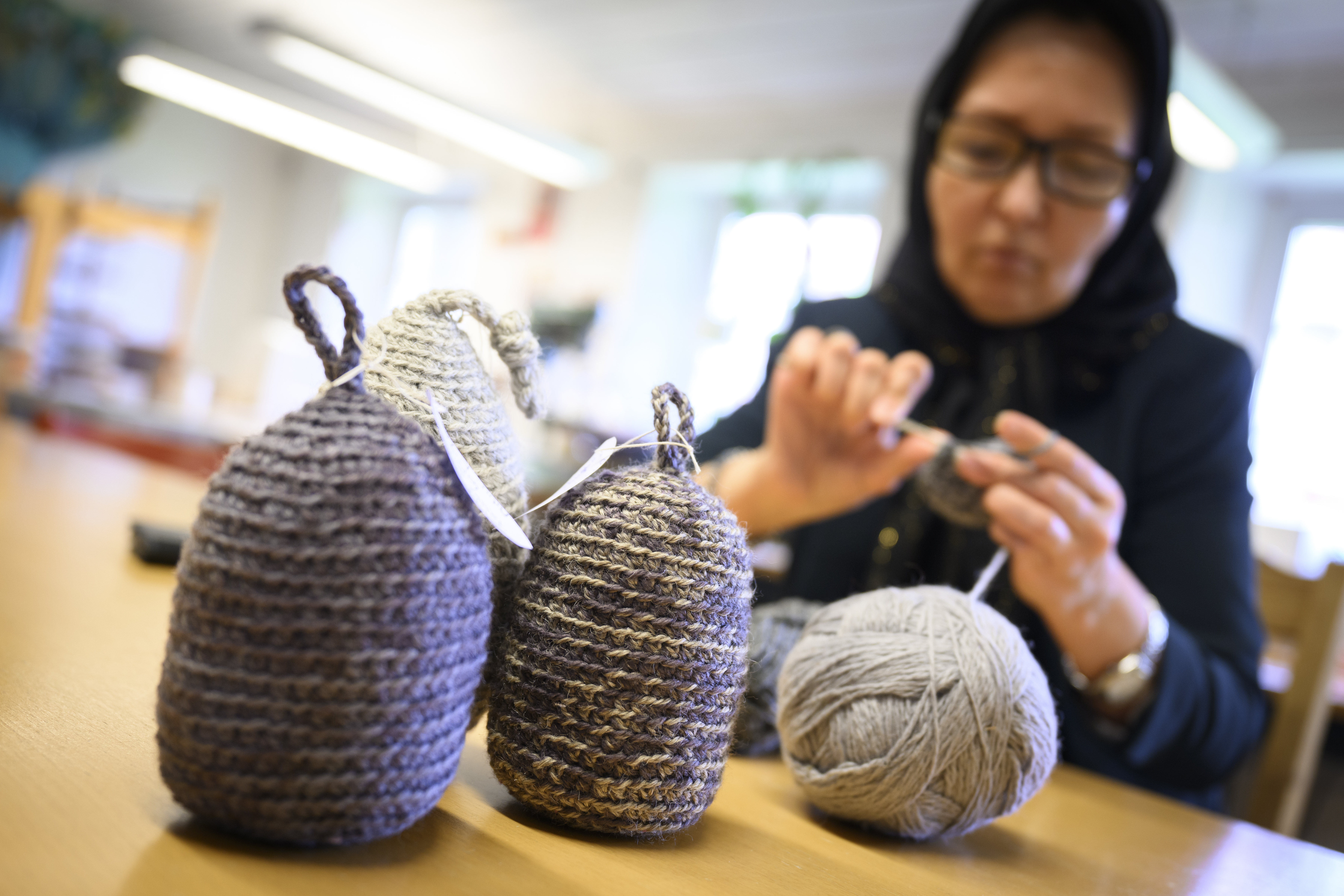 En kvinna i sjalett sitter och stickar.