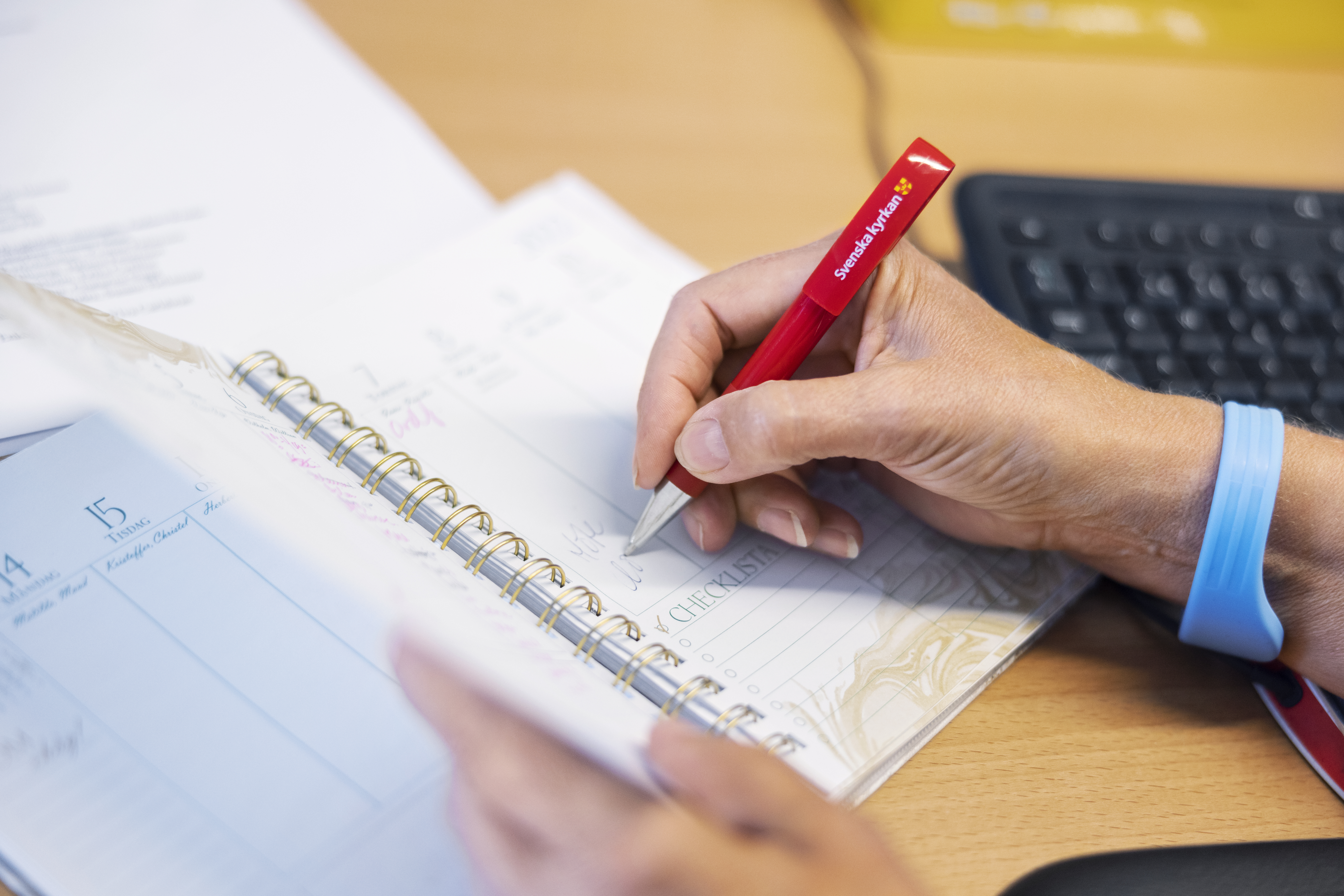 Någon antecknar i en kalender med en röd penna.