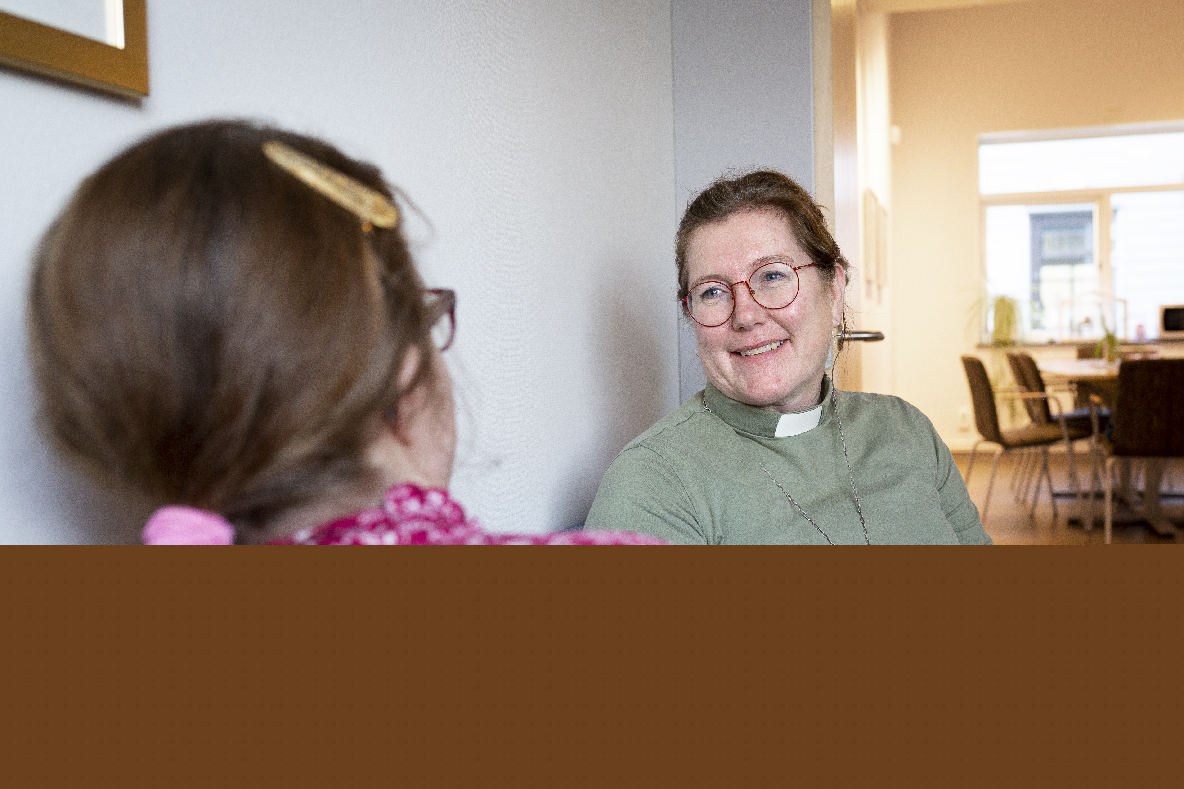 En kvinnlig diakon sitter och samtalar med en en ung tjej.