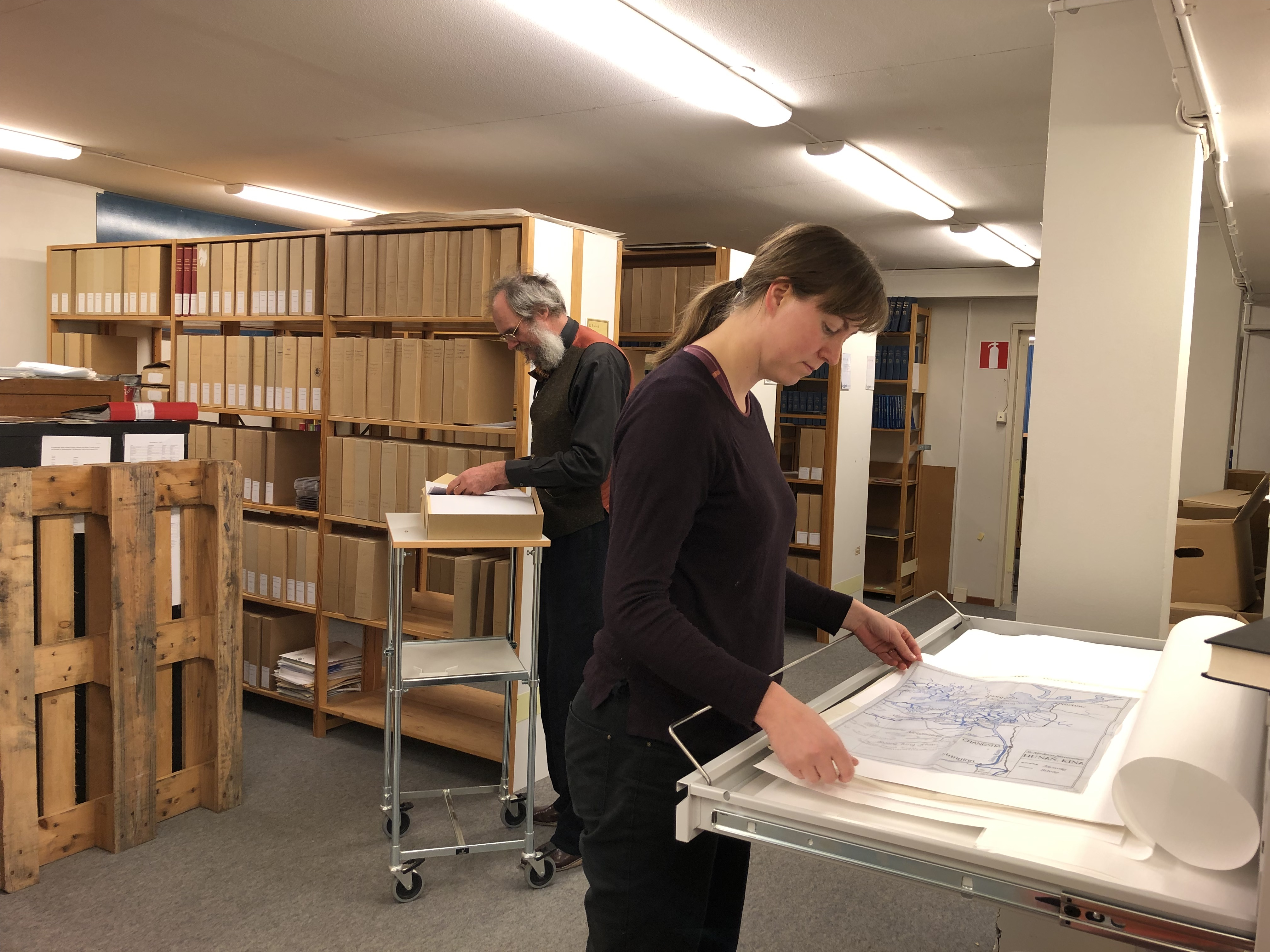 Två personer pläddrar i arkivpapper och böcker.