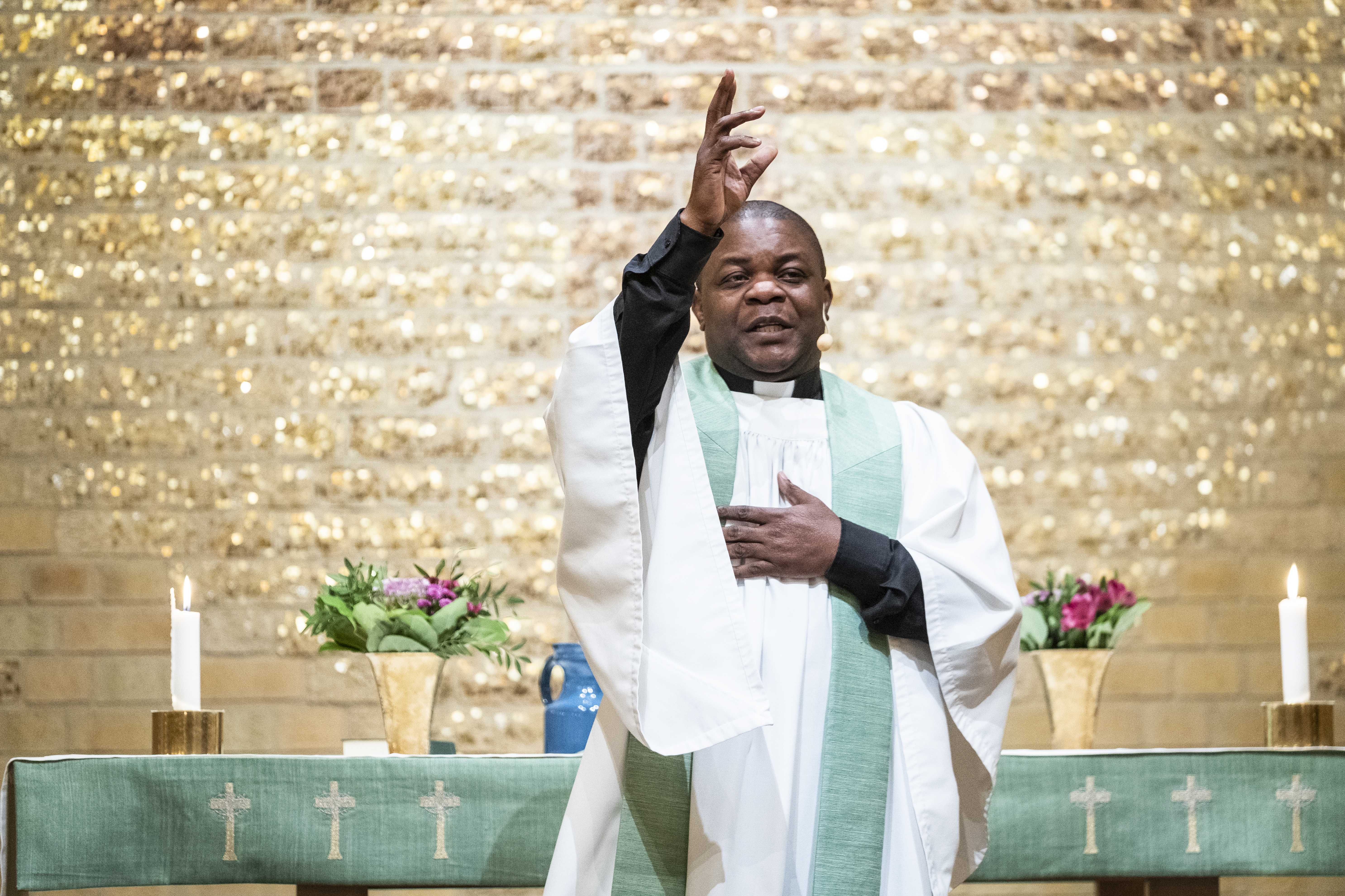 En manlig präst står framför altaret och gör ett korstecken.