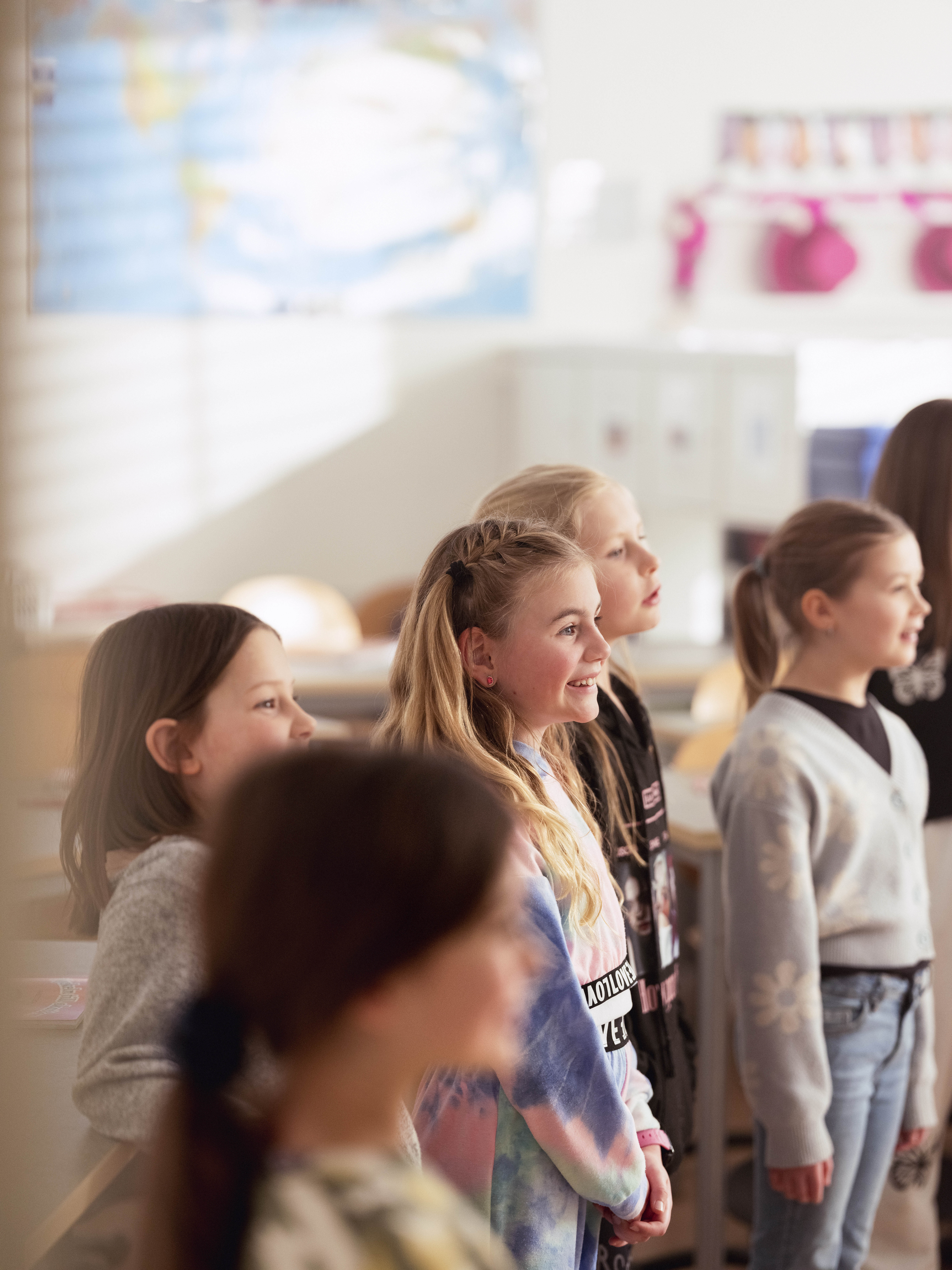 En barnkör sjunger i ett klassrum.