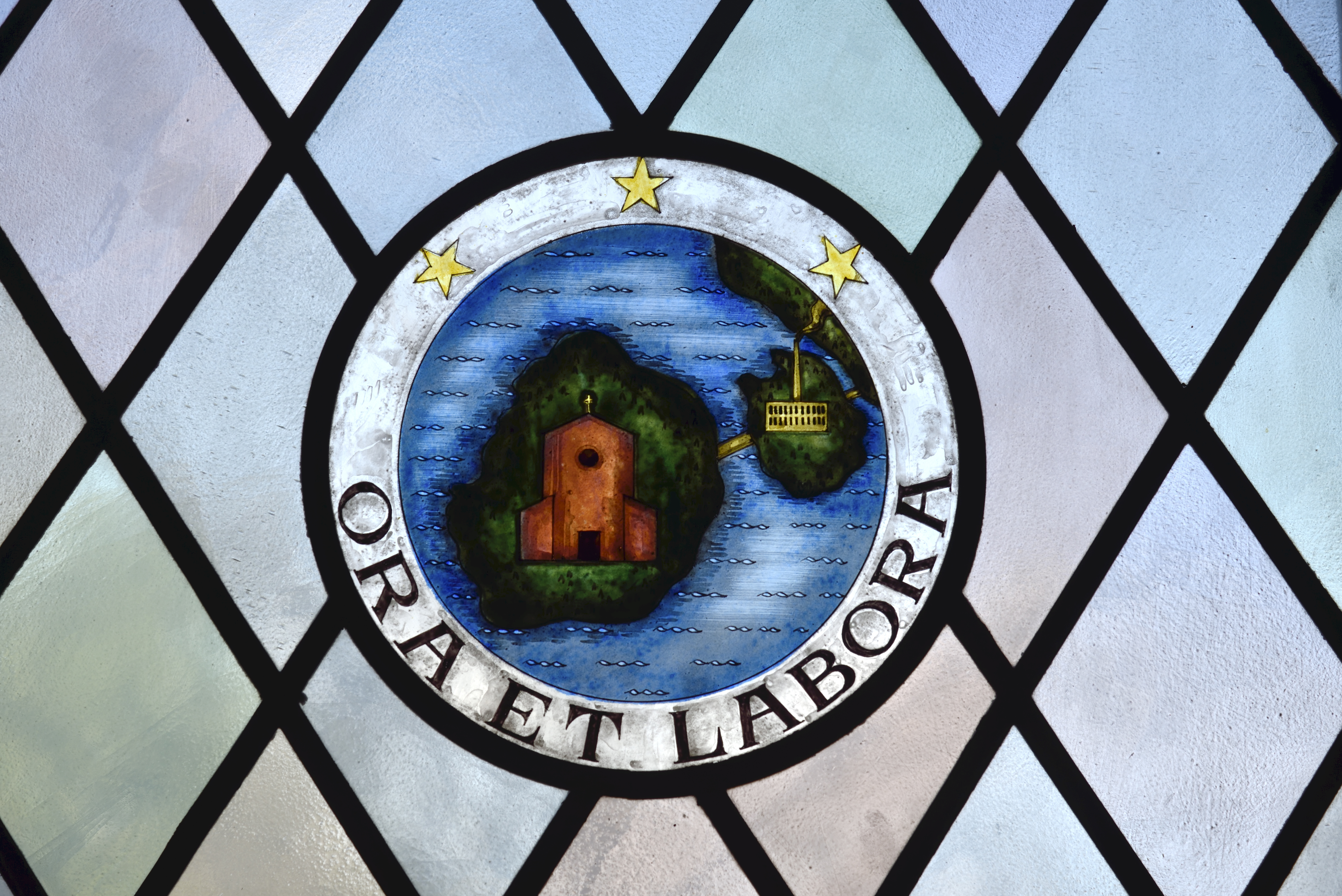 På ett målat fönster står texten Ora et labora (bön och arbete).