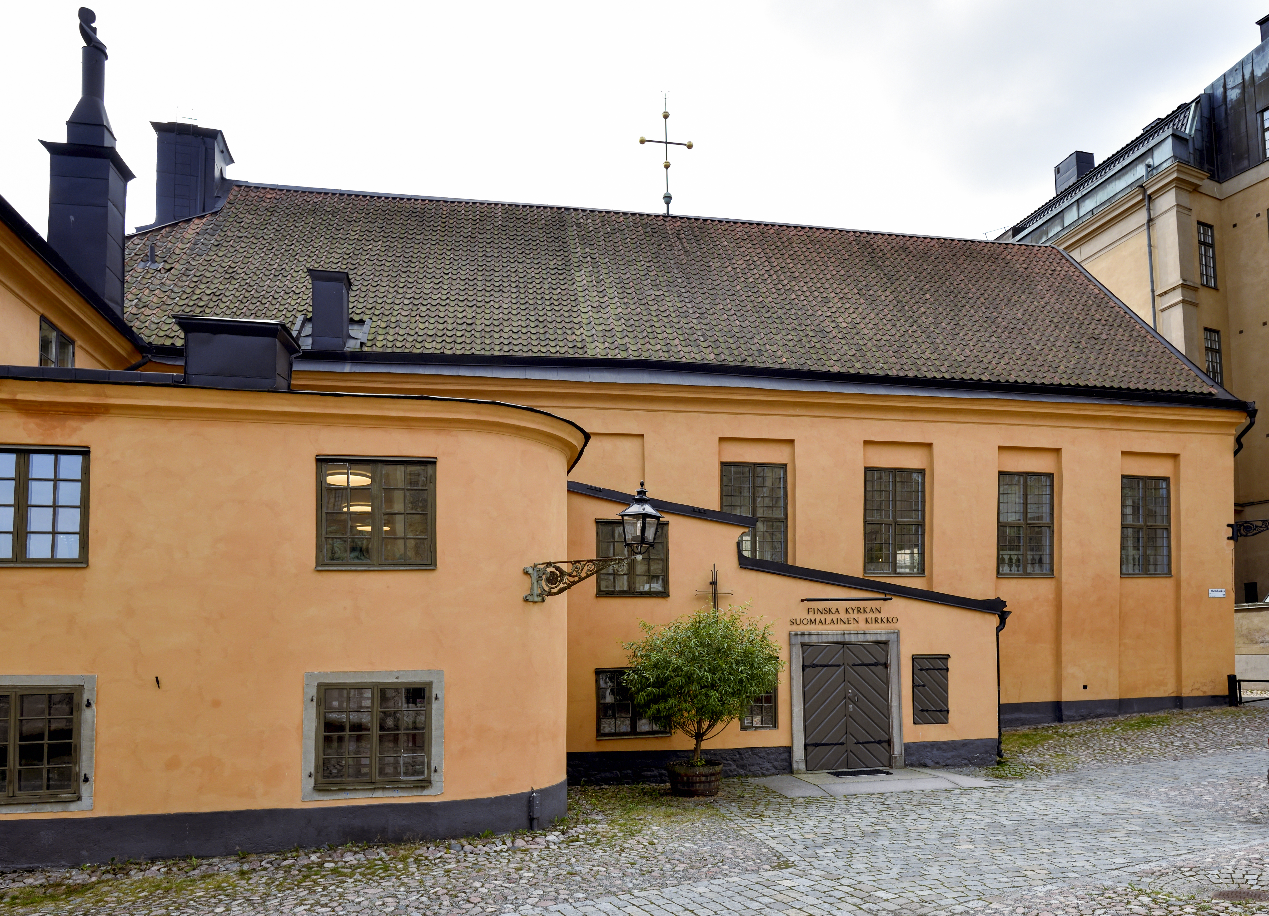Ovanför träporten på ett honungsfärgat stenhus står texten Finska kyrkan.