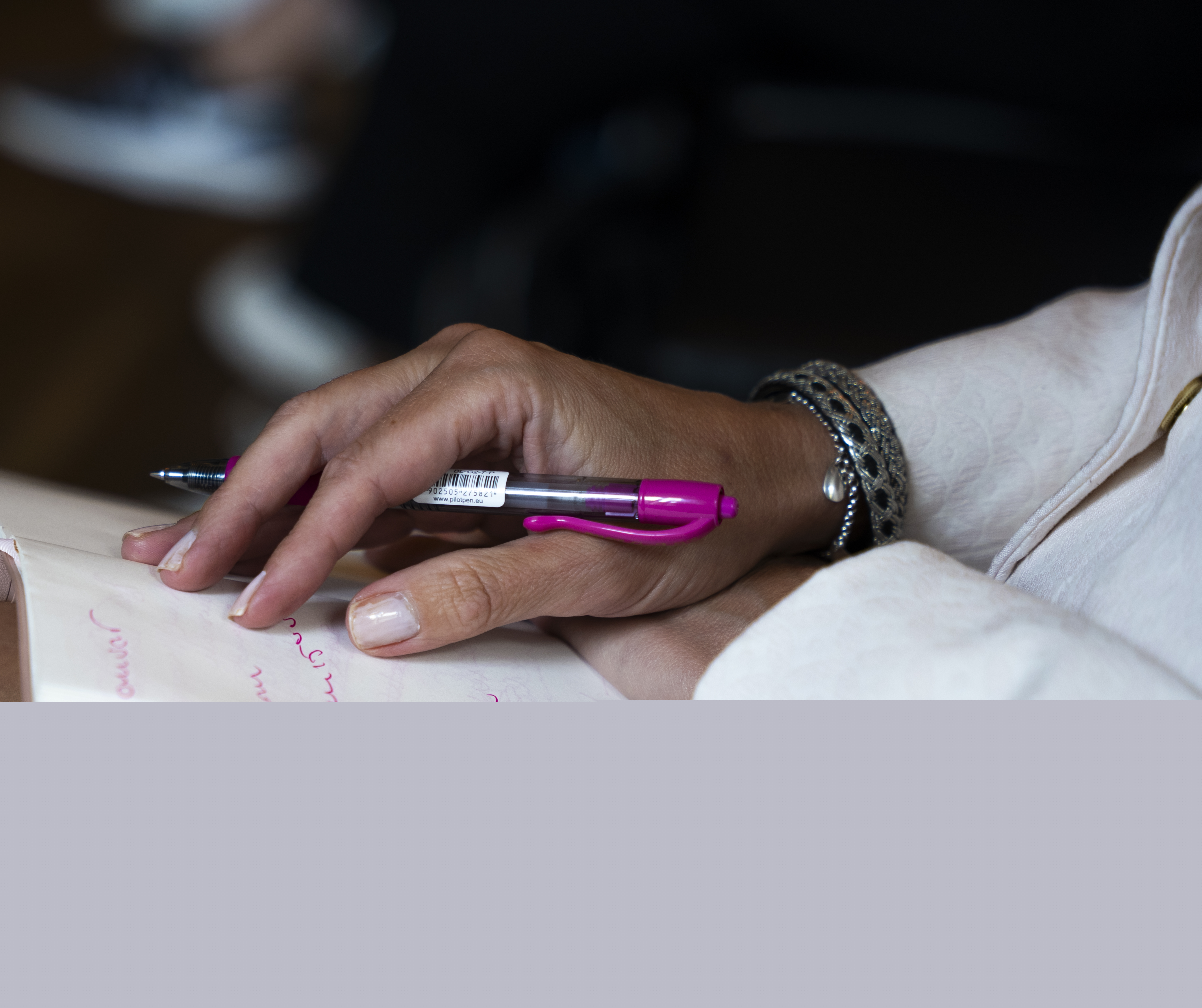 Närbild på någon som antecknar med en rosa tuschpenna.