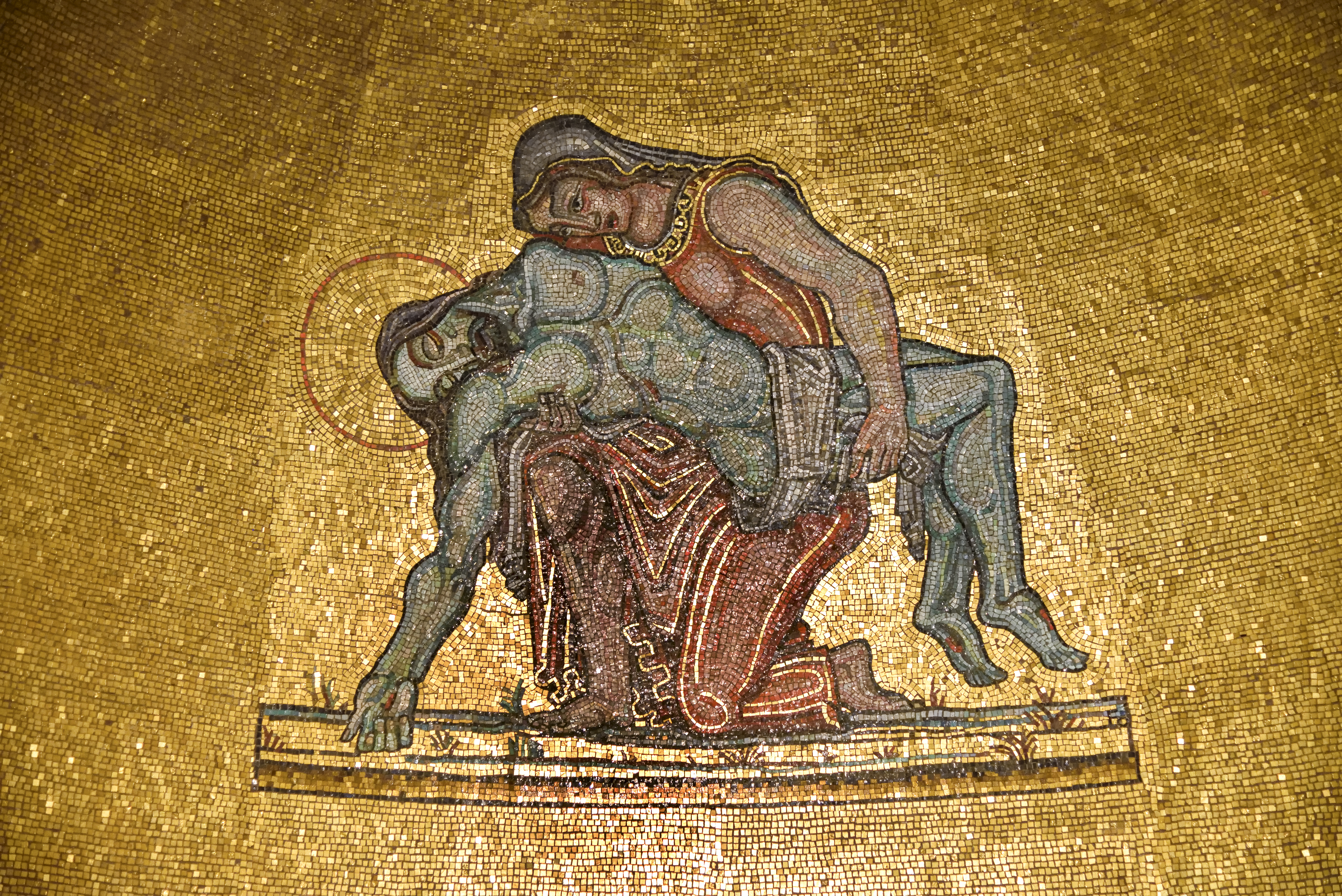 Närbild på en guldfärgad mosaikutsmyckning i ett kor föreställer Jesus när han tagits ned från korset.