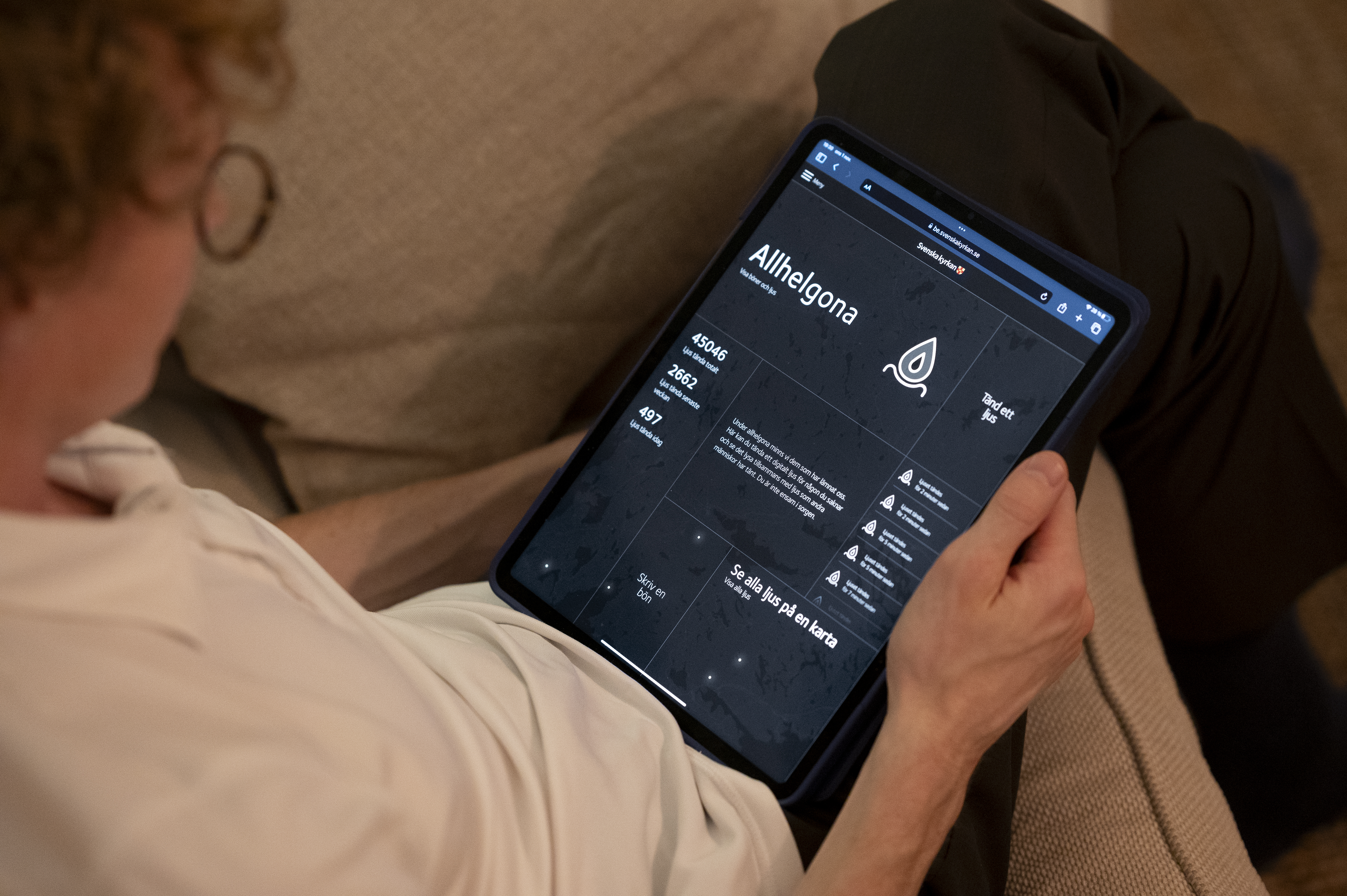 En person sitter och tittar på Svenska kyrkans bönewebb på sin surfplatta.