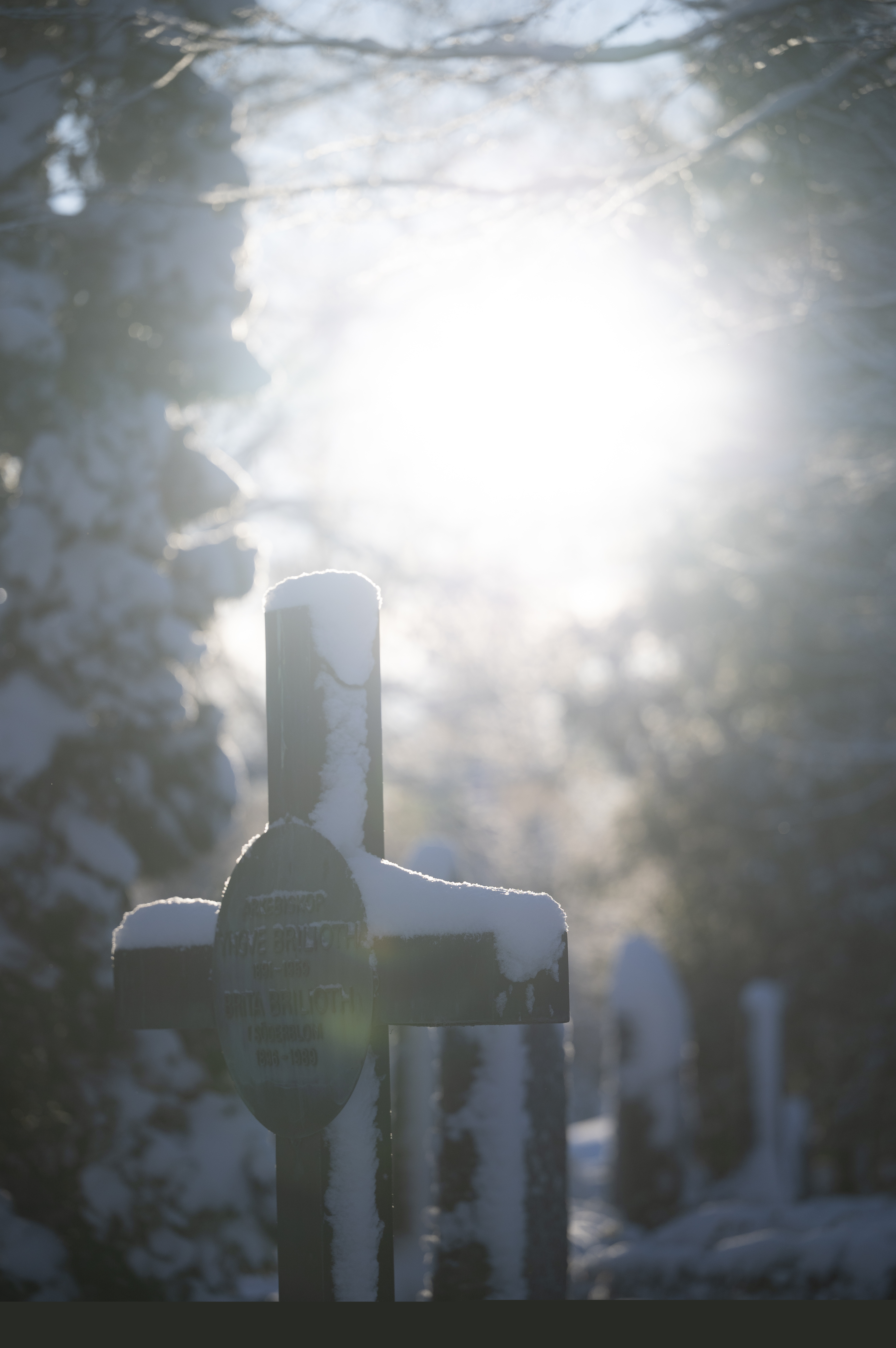 Snö ligger på en gravsten. Solen lyser.