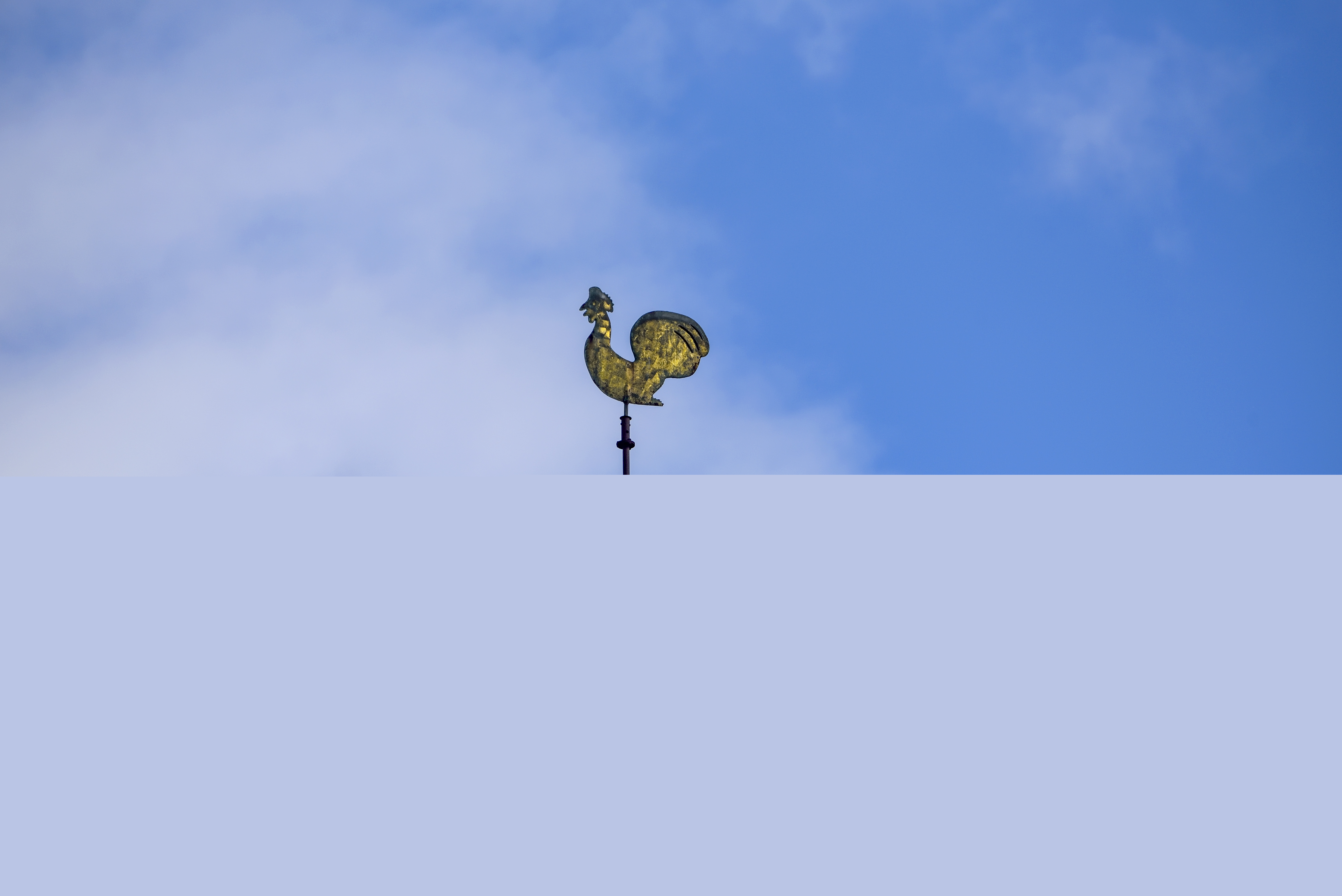 En kyrktupp mot blå himmel.