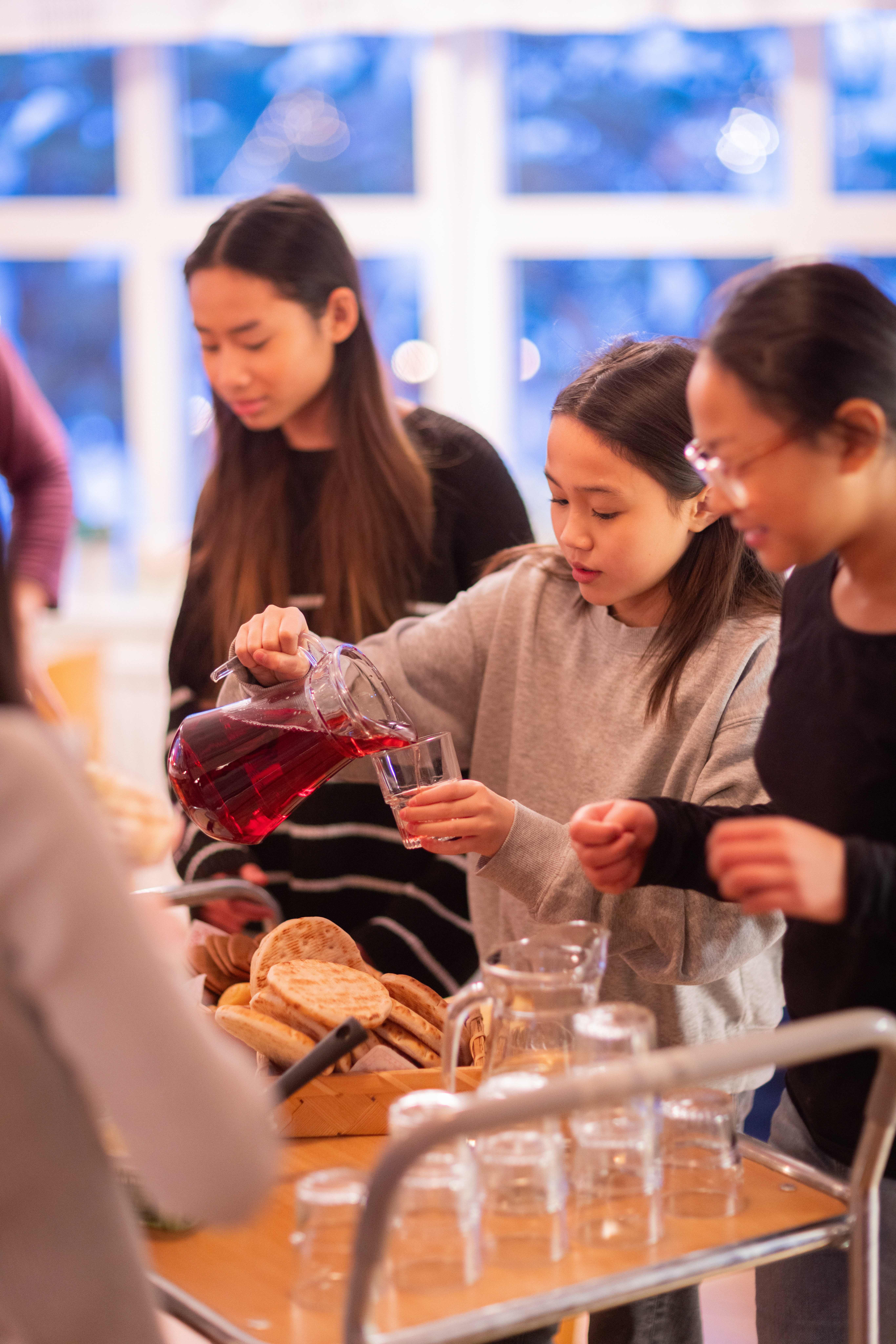 En flicka vid en fikavagn häller upp saft i ett glas. Andra flickor står bredvid.