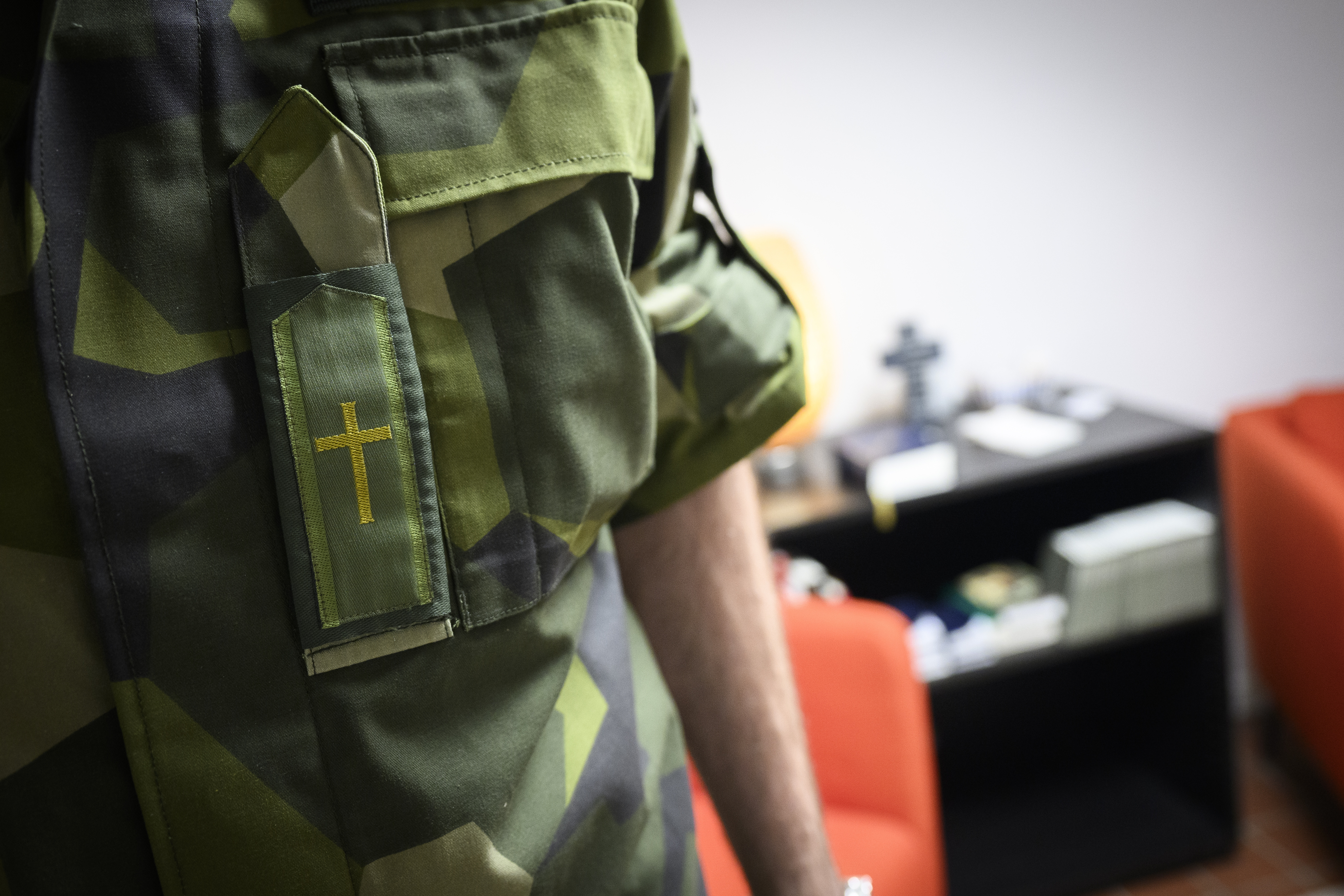 Närbild på kamouflagefärgade kläder med ett broderat kors.