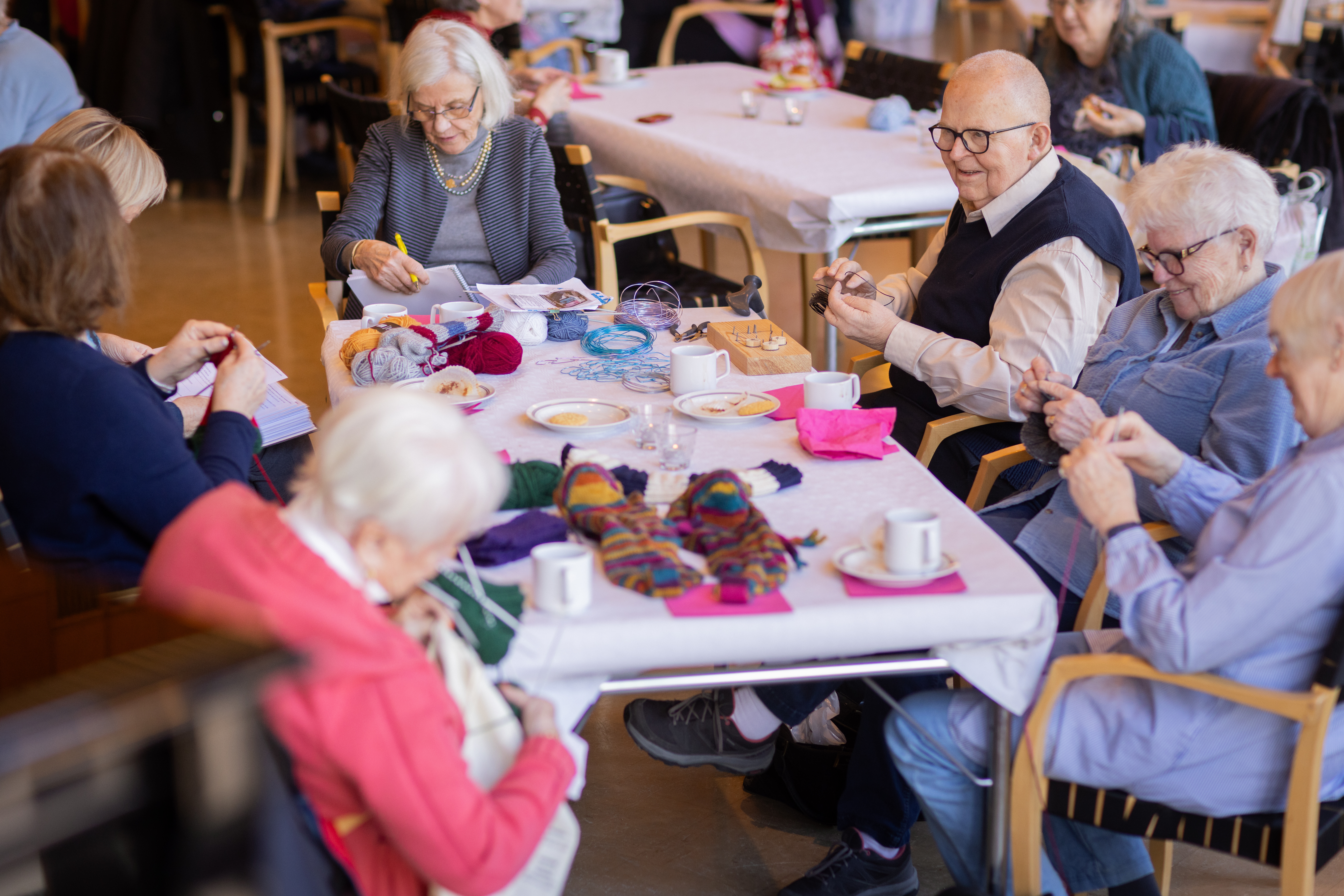 Flera äldre personer sitter vid ett bord och pysslar.