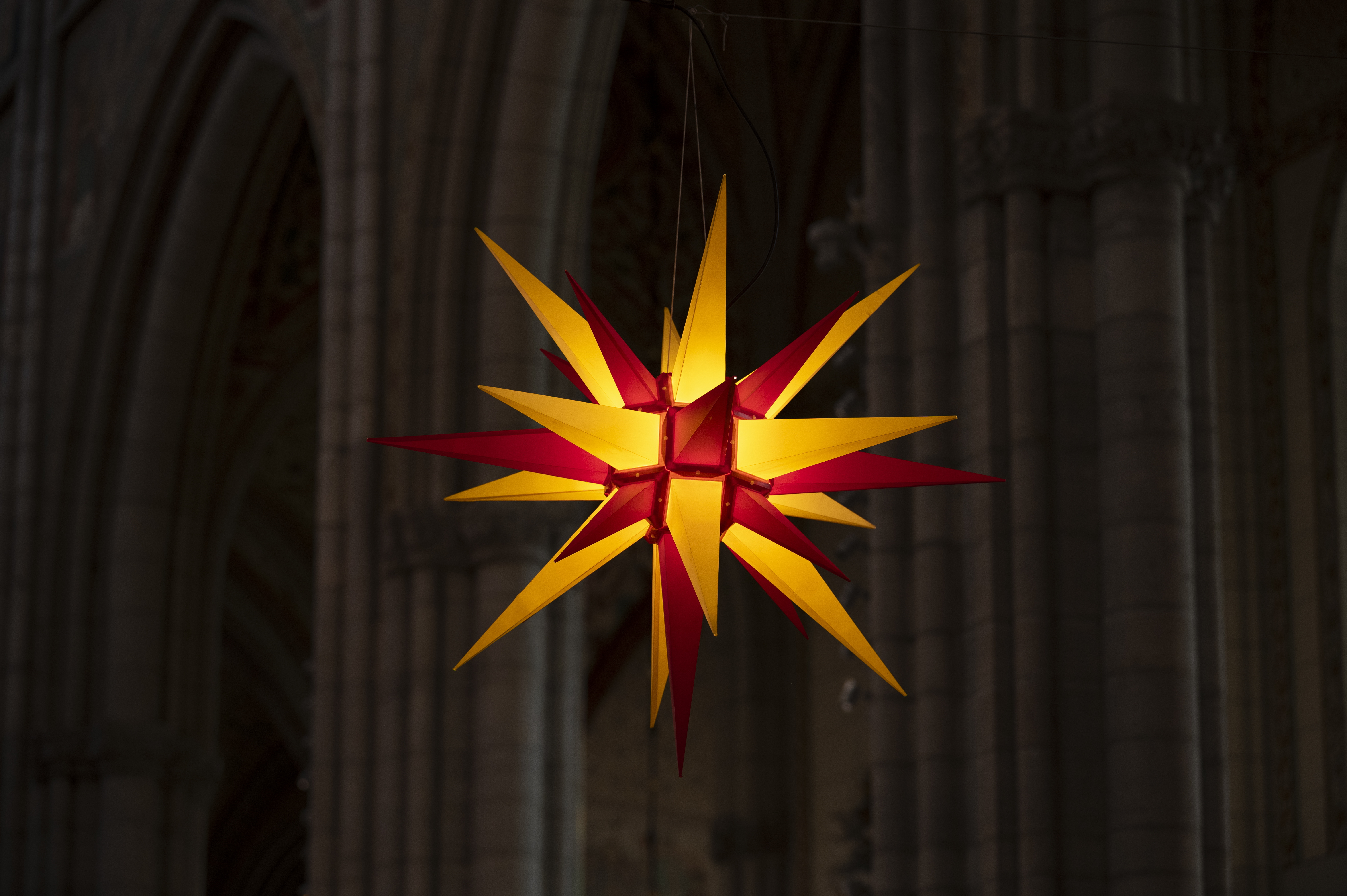 En tänd julstjärna i gult och rött hänger i Uppsala domkyrka.