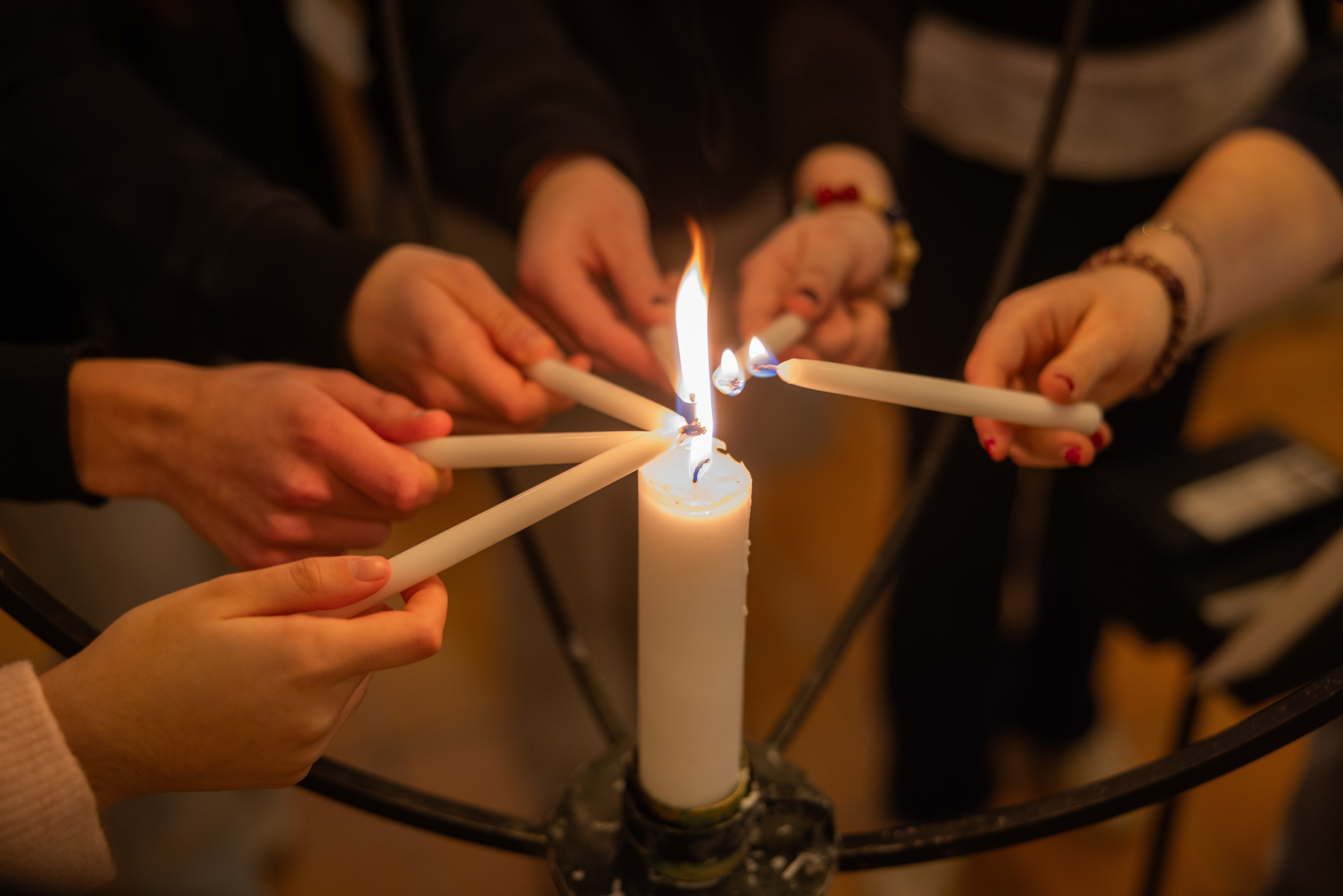 Ungdomar tänder egna små ljus från ett stort levande ljus.