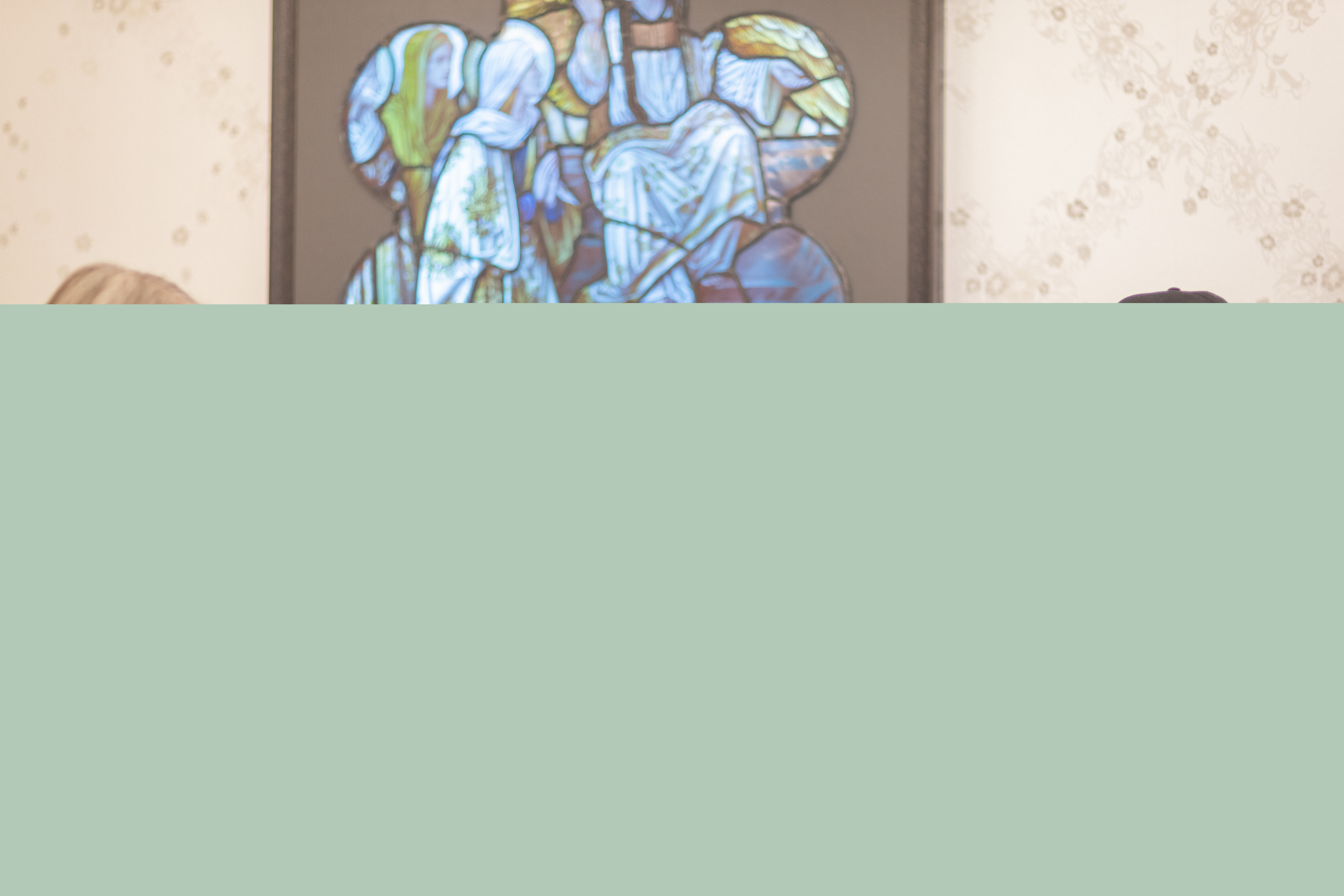 Två kvinnor och en man sitter och samtalar kring ett bord. På väggen bakom hänger en tavla i blå och gröna färger.