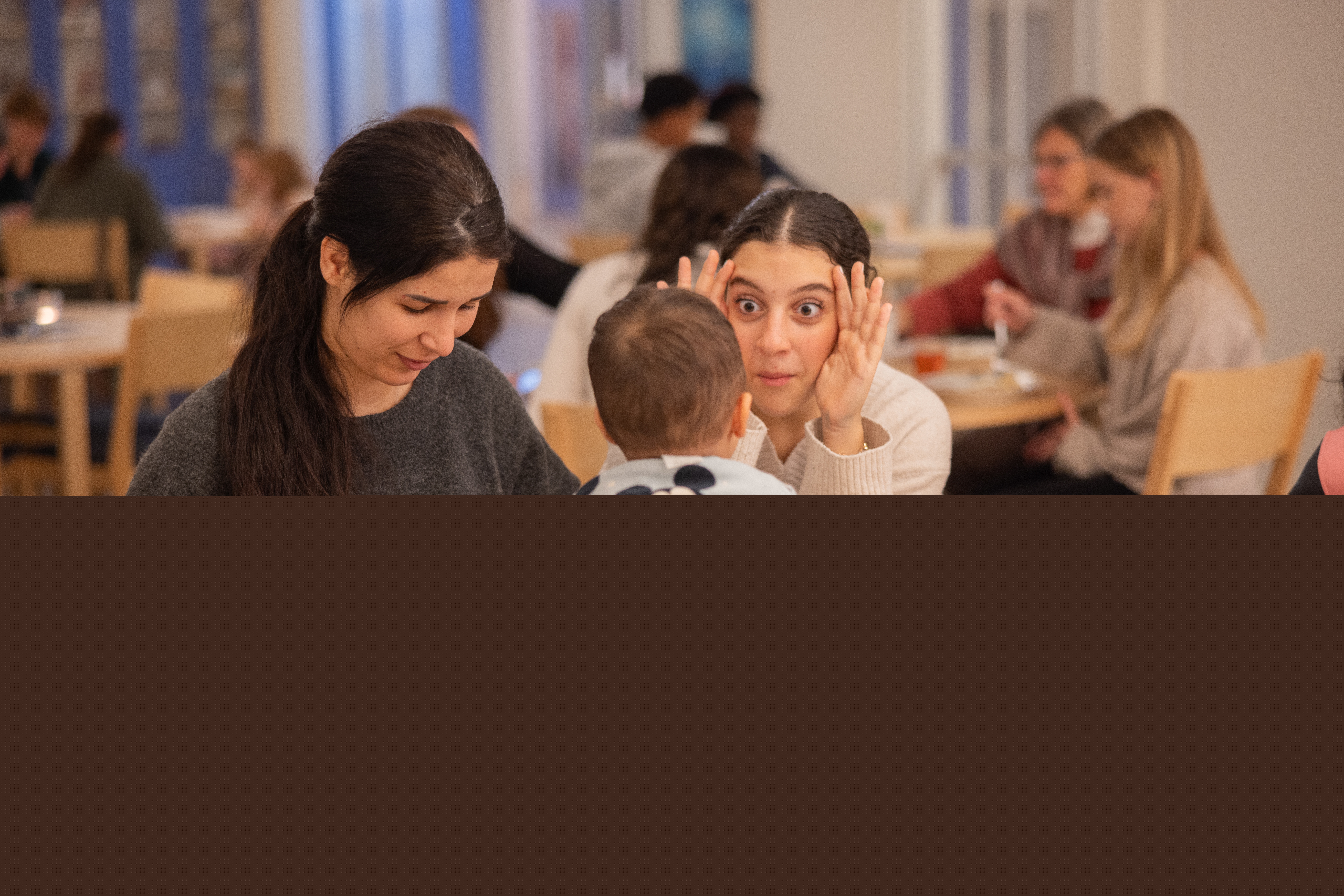 En tjej leker tittut med en liten pojke som sitter på ett bord.