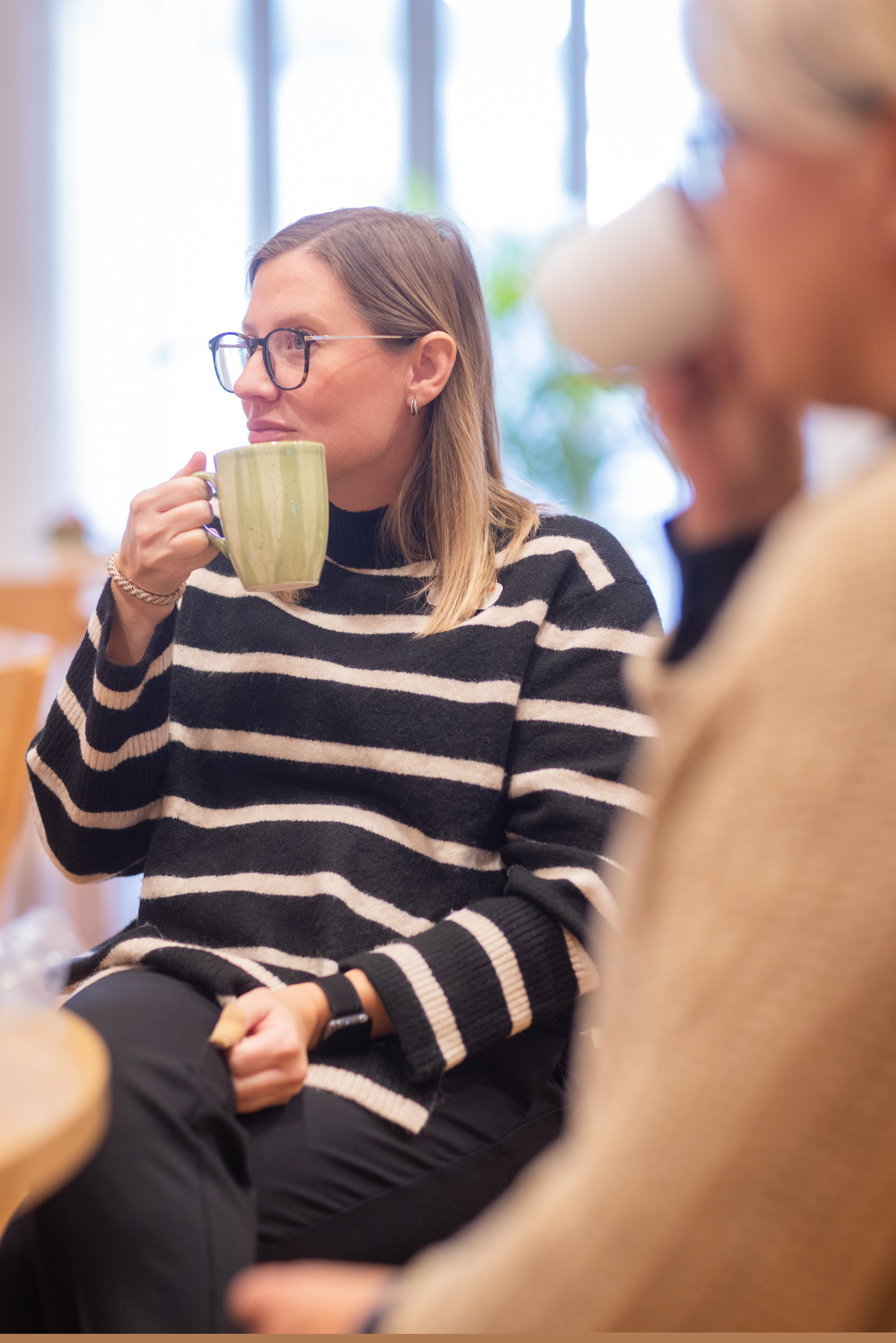 Två kvinnor sitter vid ett bord och fikar tillsammans.