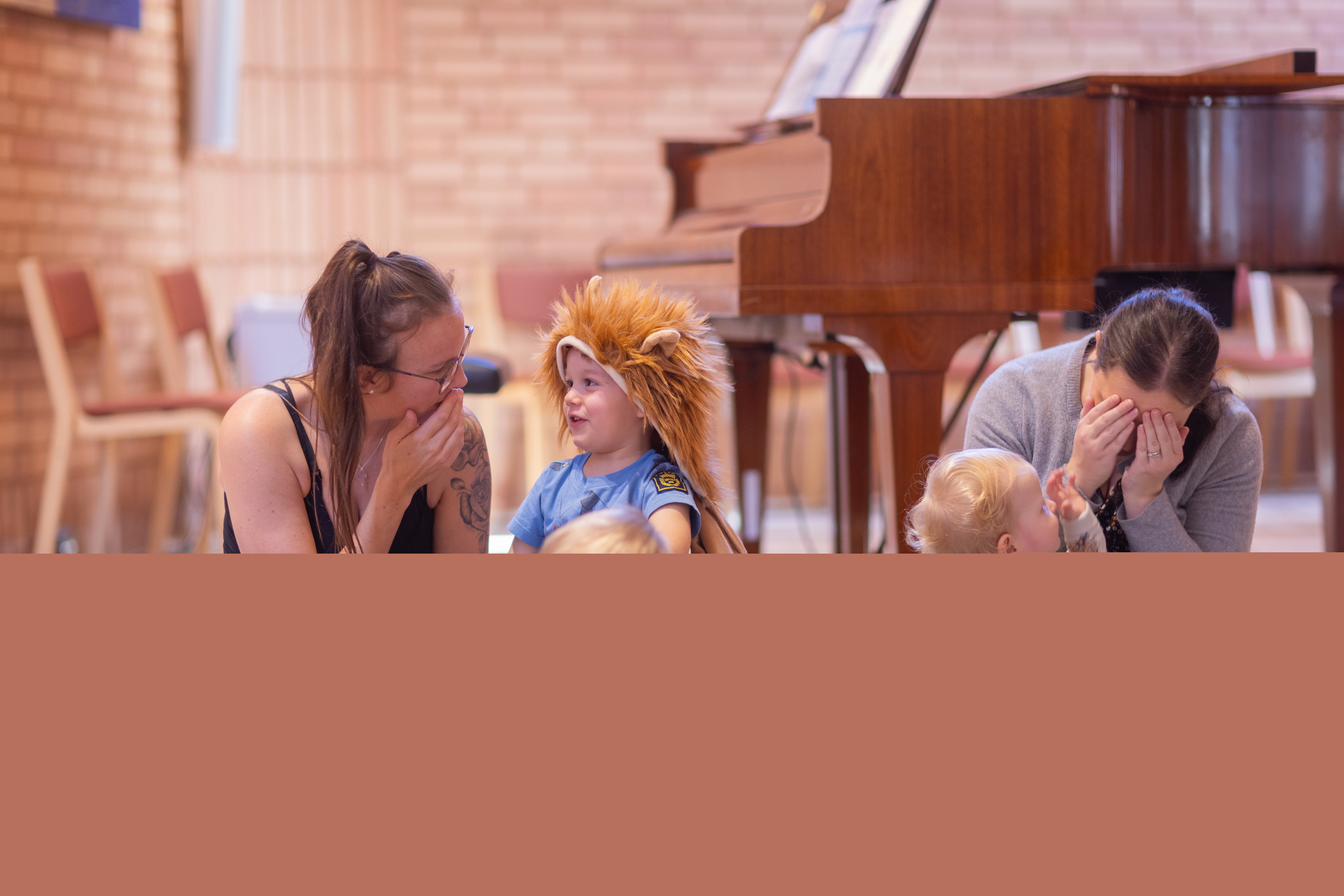 Två kvinnor sitter på golvet och leker med barnen på en öppen förskola.