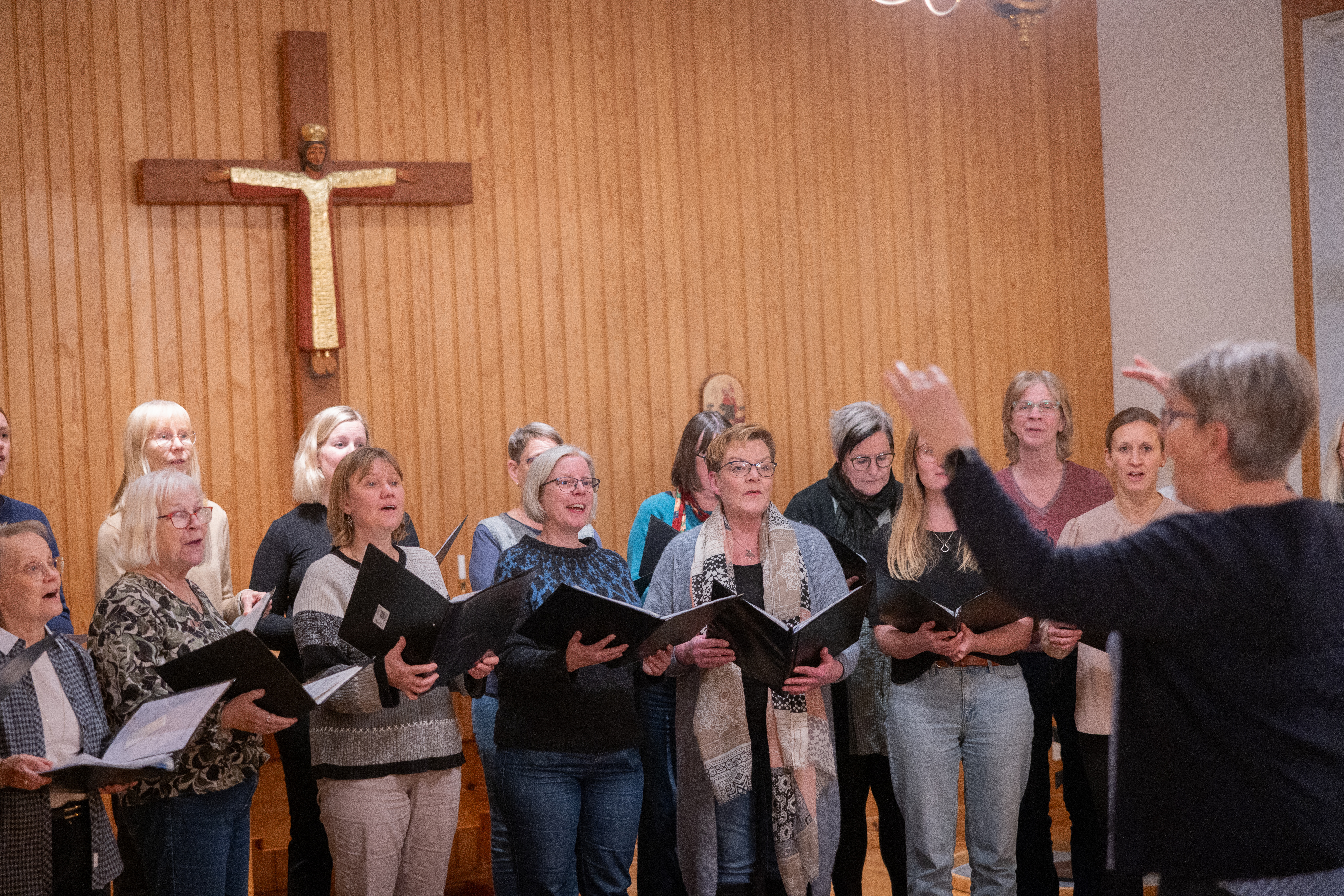 En dirigent leder en damkör i en kyrka.