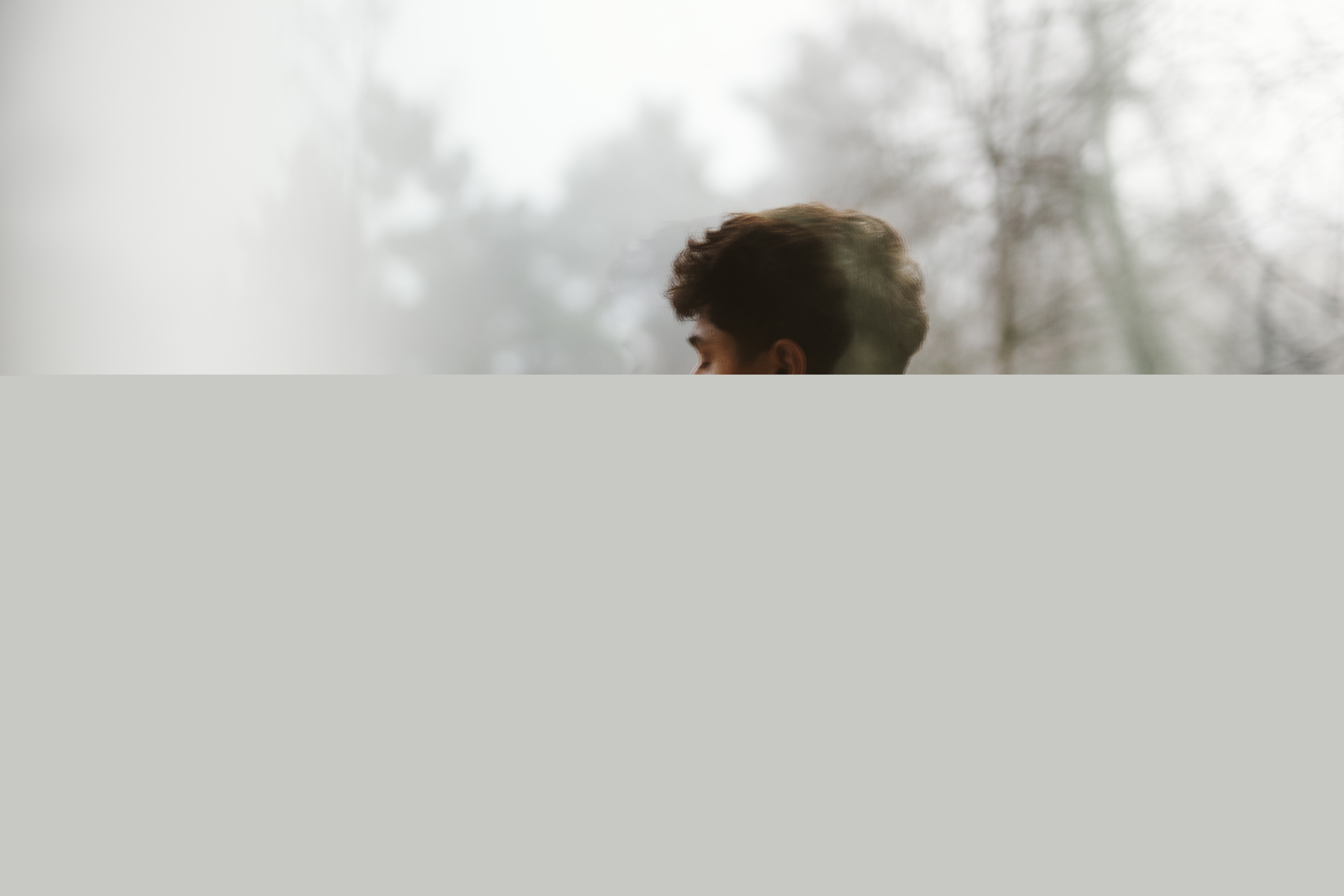 En ung man utomhus. Träd och dimma i omgivningen.