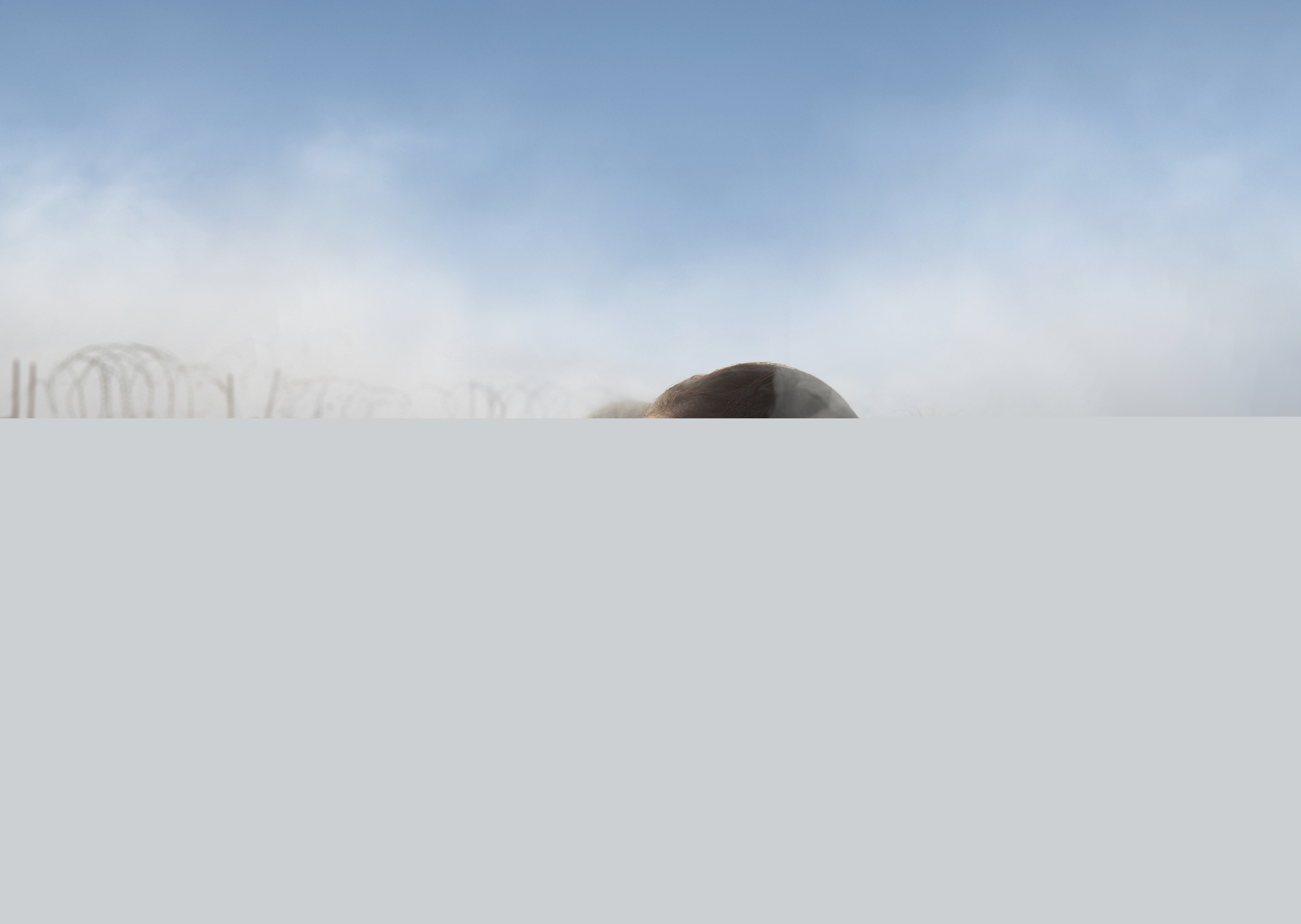 Två kvinnor. Bakom dem syns rök, staket och våldsamma upplopp.