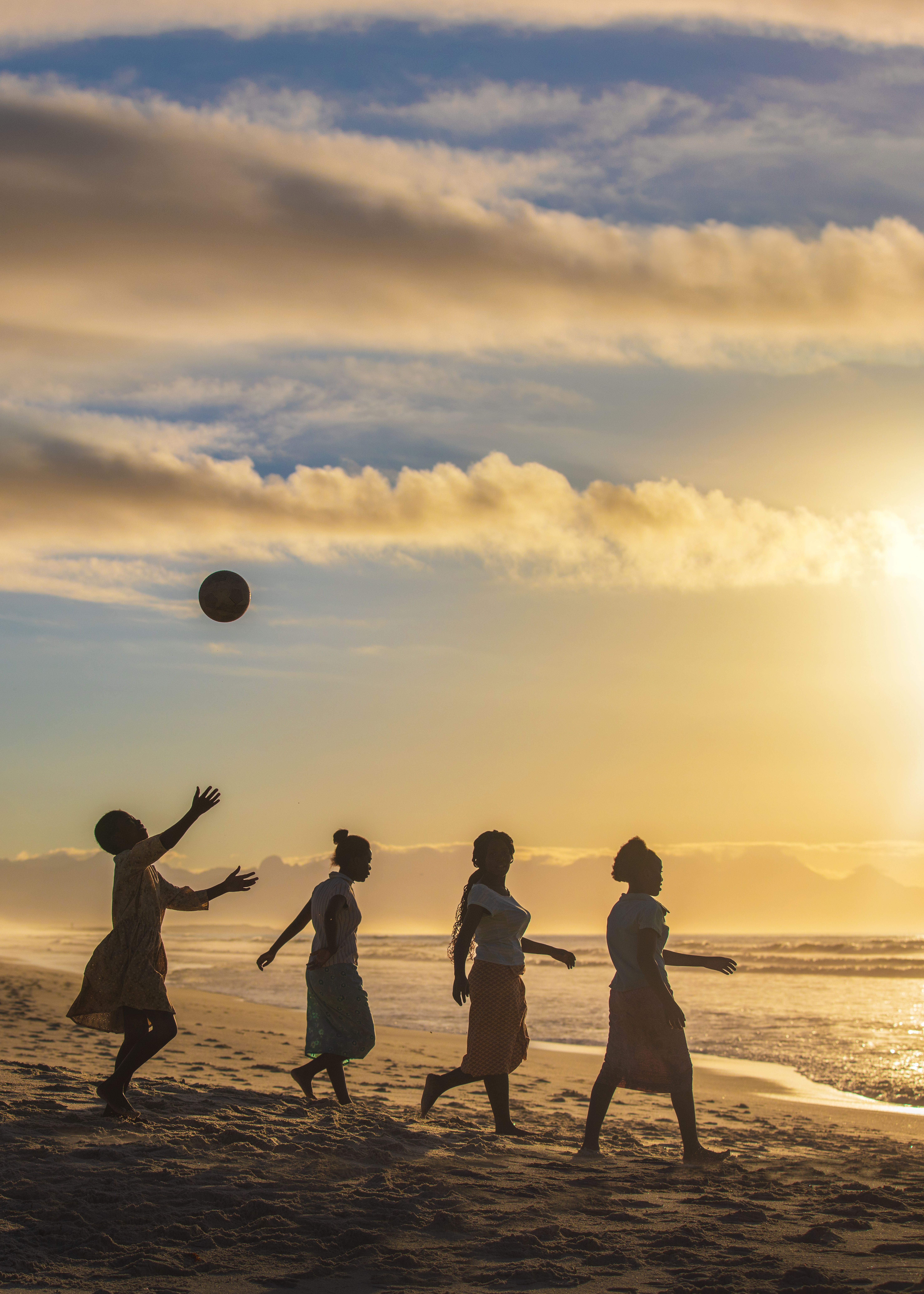 Fyra kvinnor på en strand i solnedgång.